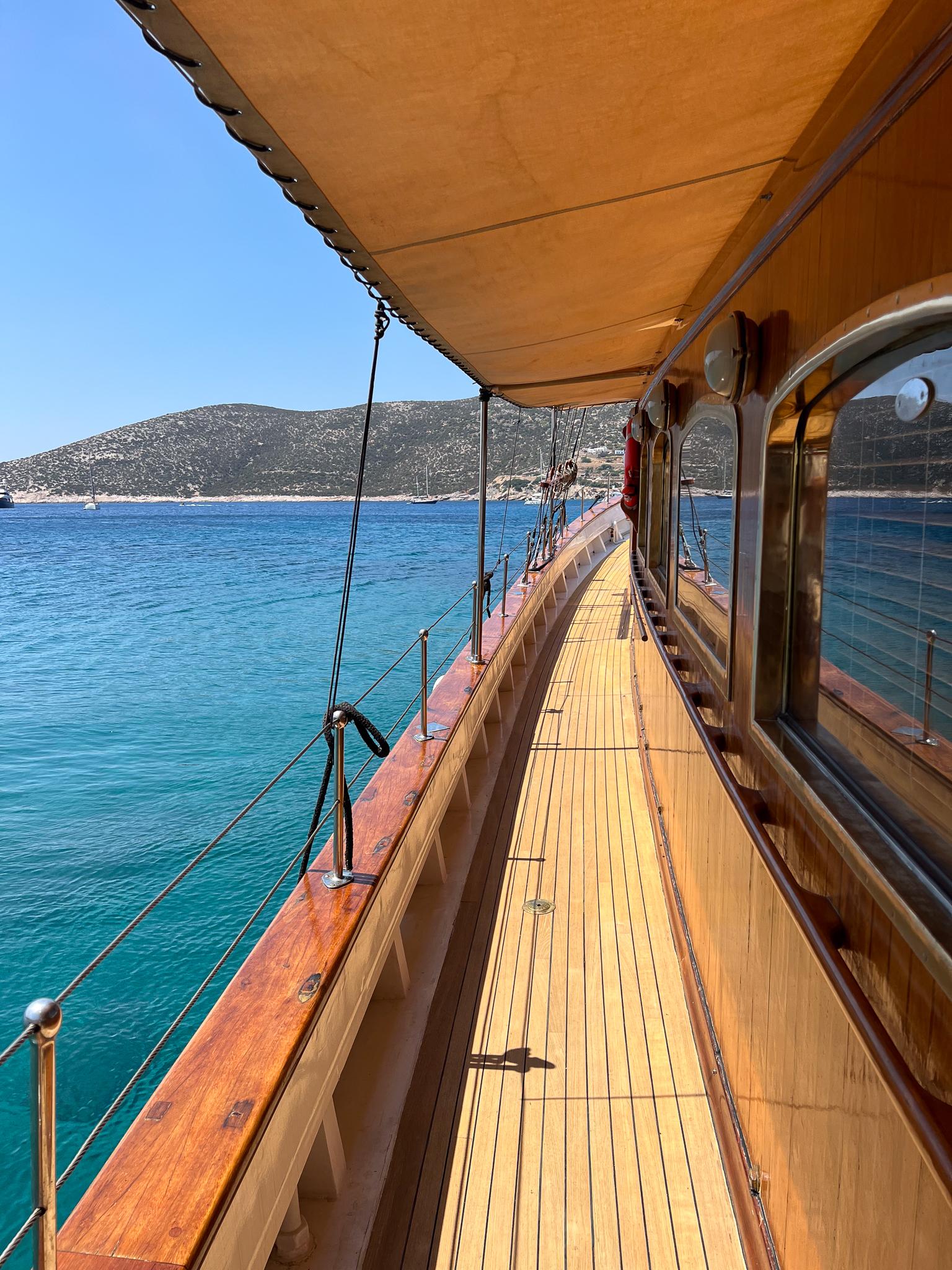 Wooden deck of a 1969 Psarros Shipyard yacht cruising on clear blue waters.