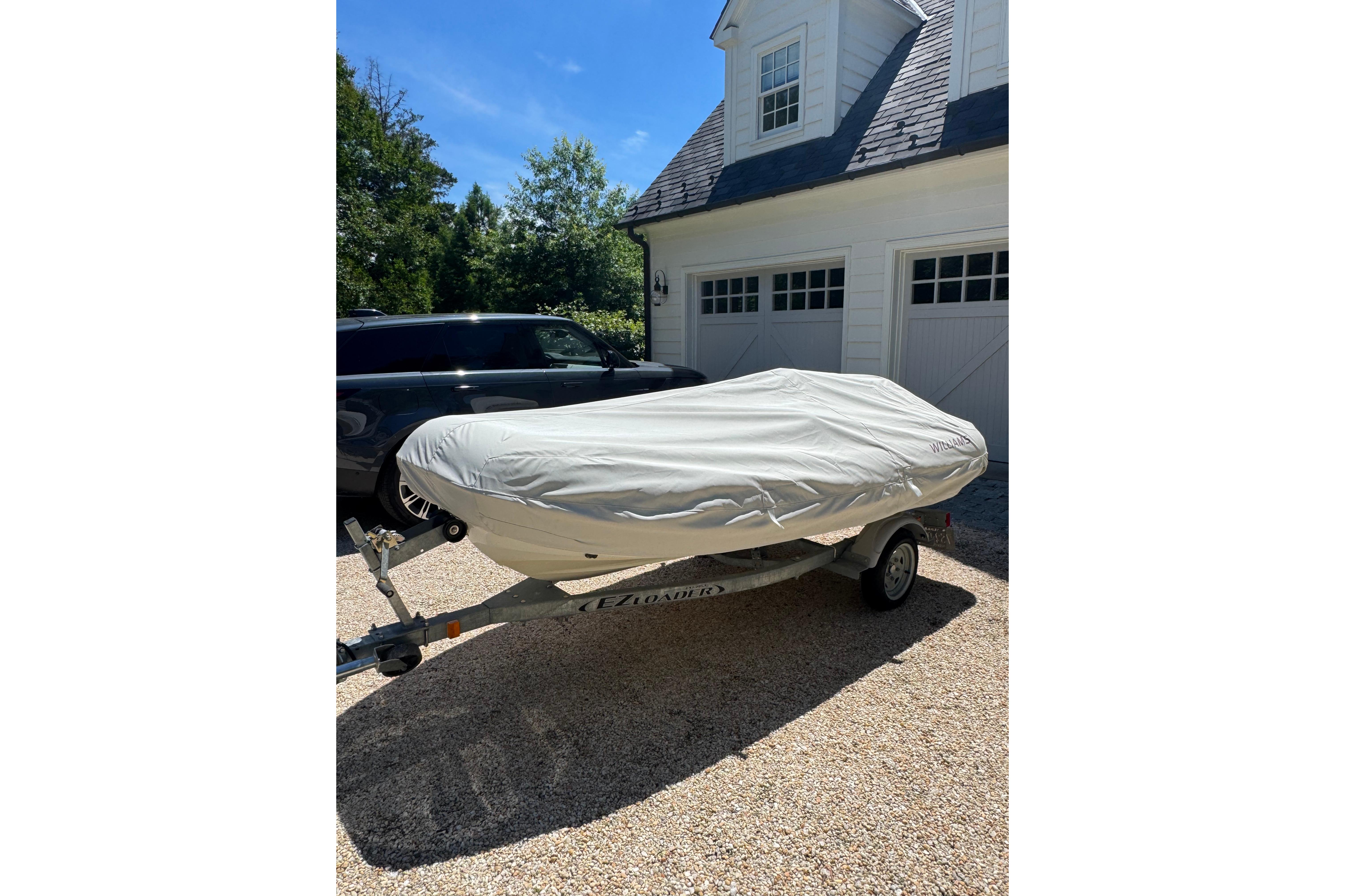 Covered 2017 Williams Jet Tenders Turbojet 325 on trailer, parked in driveway.