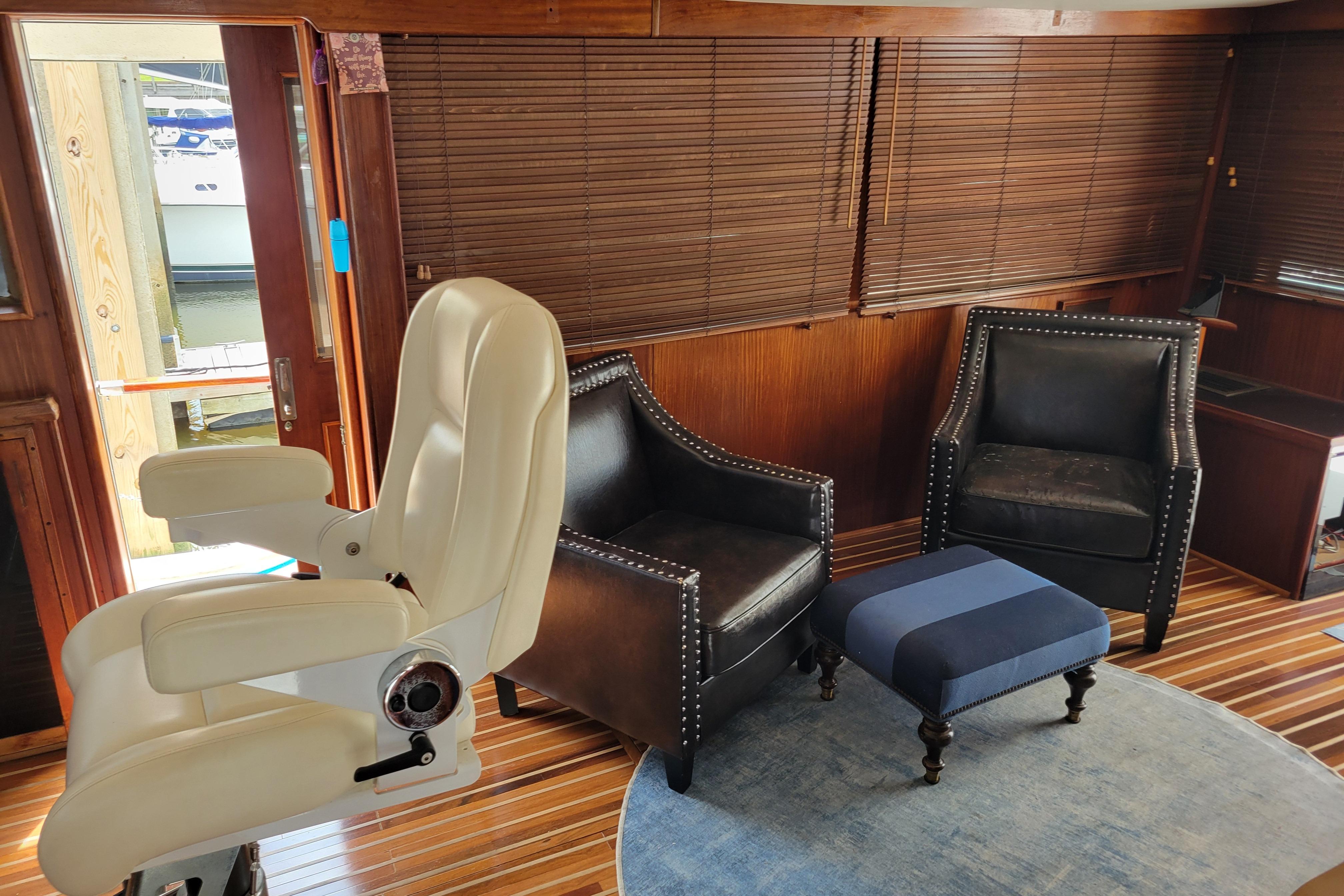 Interior of 1980 Hatteras 53 Yacht Fisherman with leather chairs and striped ottoman.