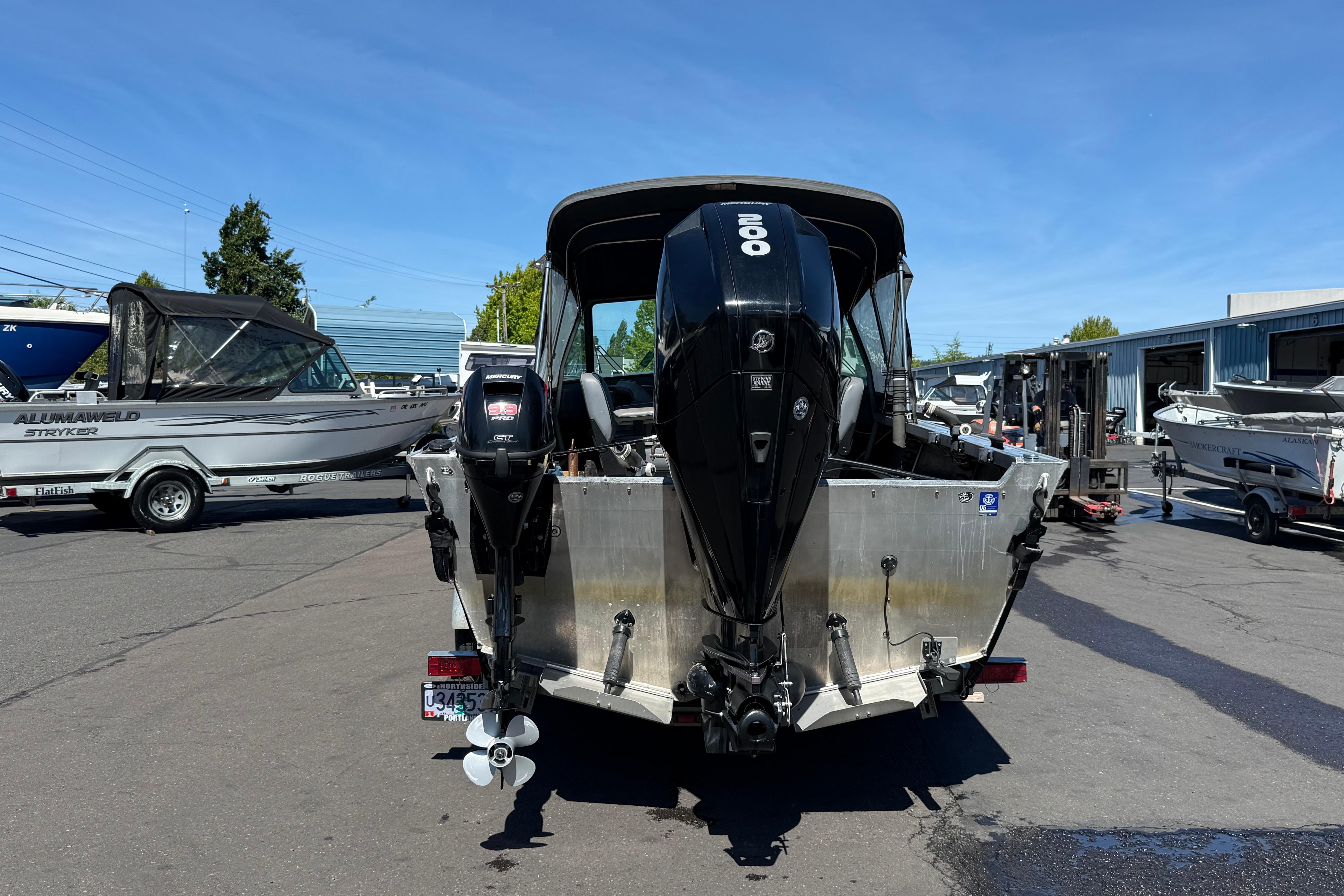 2004 Alumaweld Intruder Outboard 20 boat with powerful engine, parked outdoors on a sunny day.