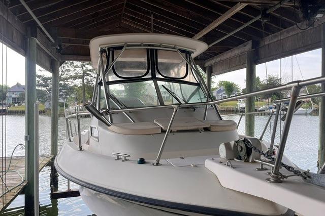 2002 Grady-White Gulfstream 232 boat docked under a wooden shelter.