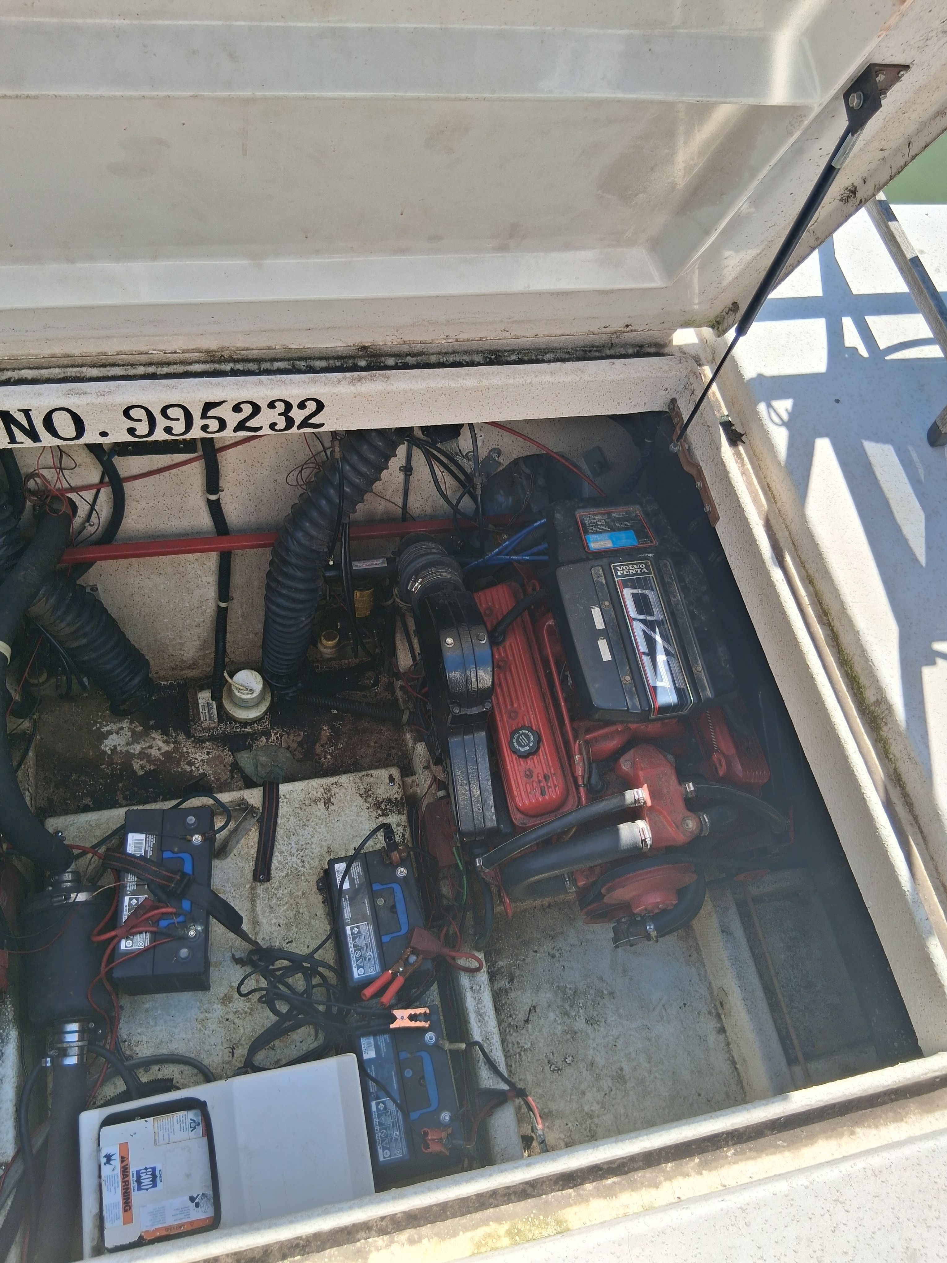 An open engine compartment of a boat showing an engine and several batteries.