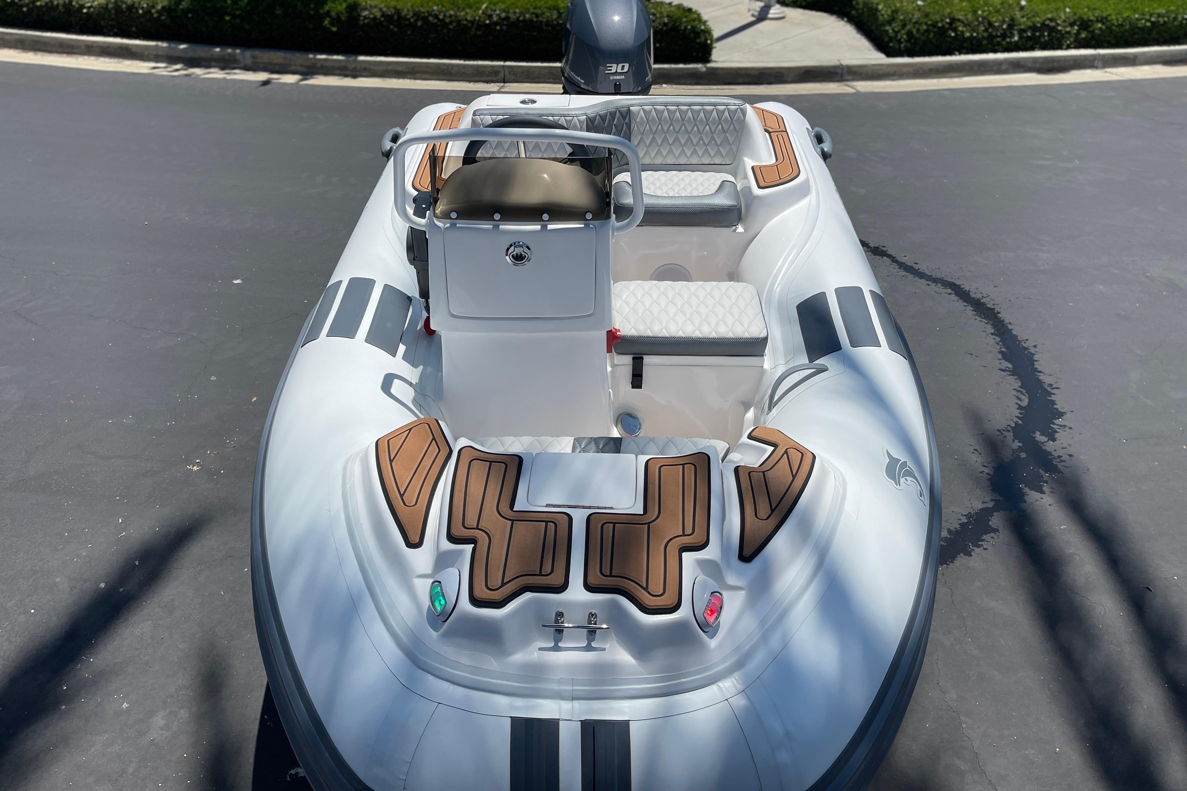 2025 Caribe DL11 inflatable boat with seating and console, parked on pavement.