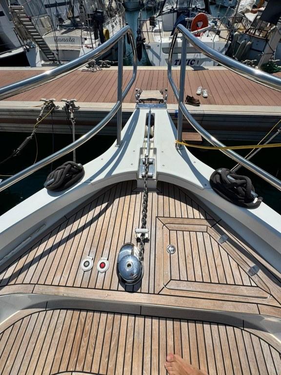 Bow of 2022 Rodman 1290 Evolution yacht with wooden deck and metal railings.