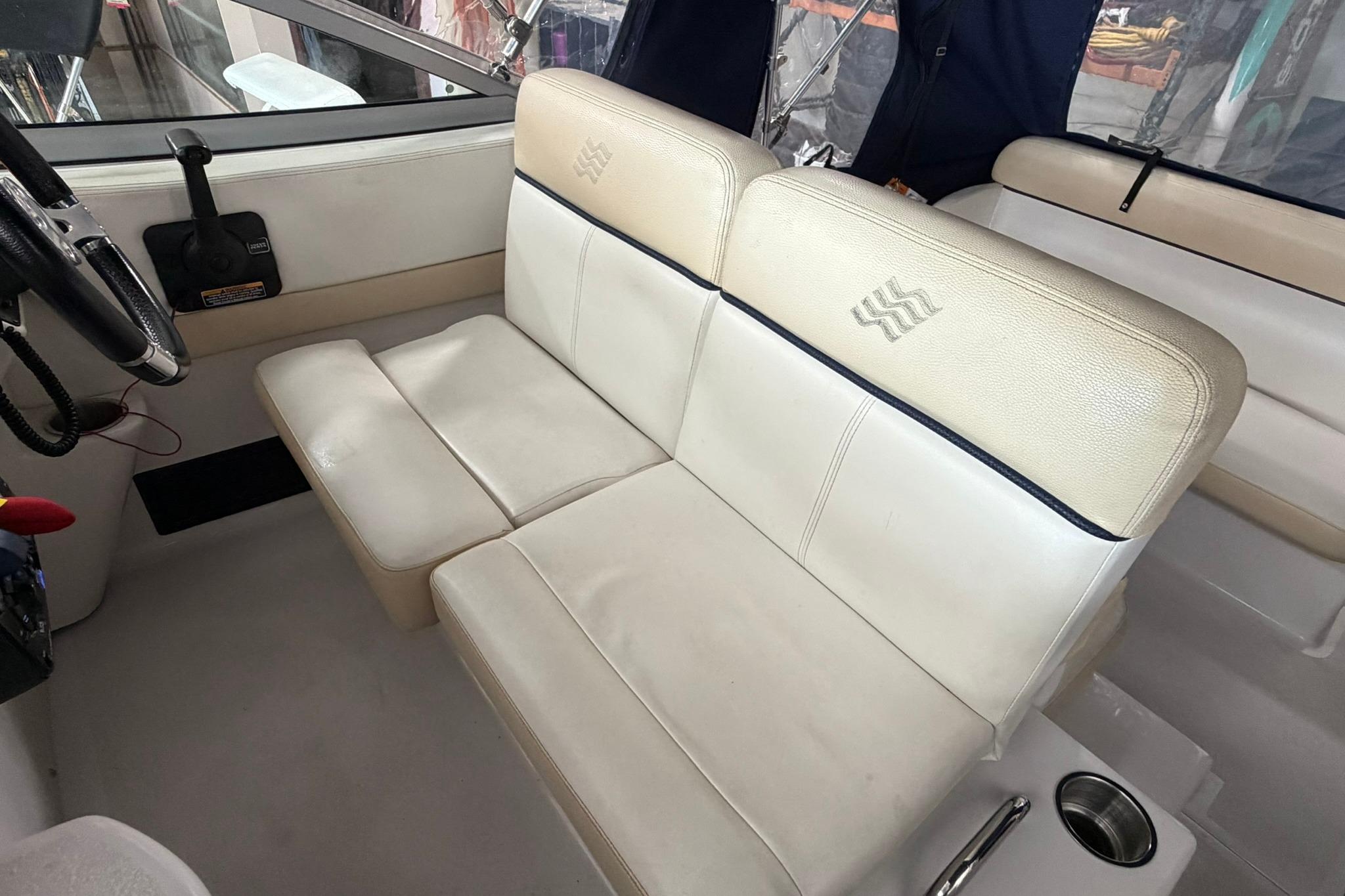 Interior of 2008 Four Winns V248 boat with white leather seating and steering wheel.