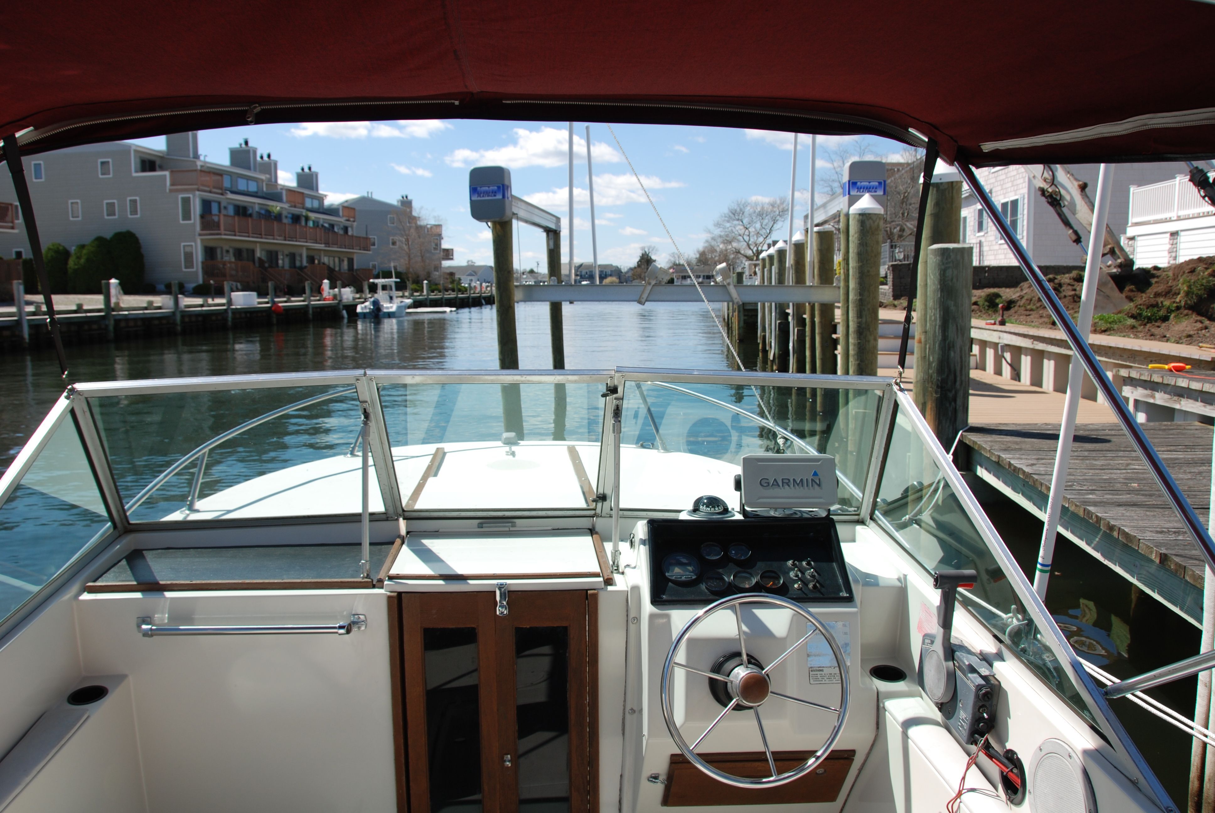 The cockpit of a 1987 Wellcraft V-20 Steplift with steering wheel and instruments, in a harbor.