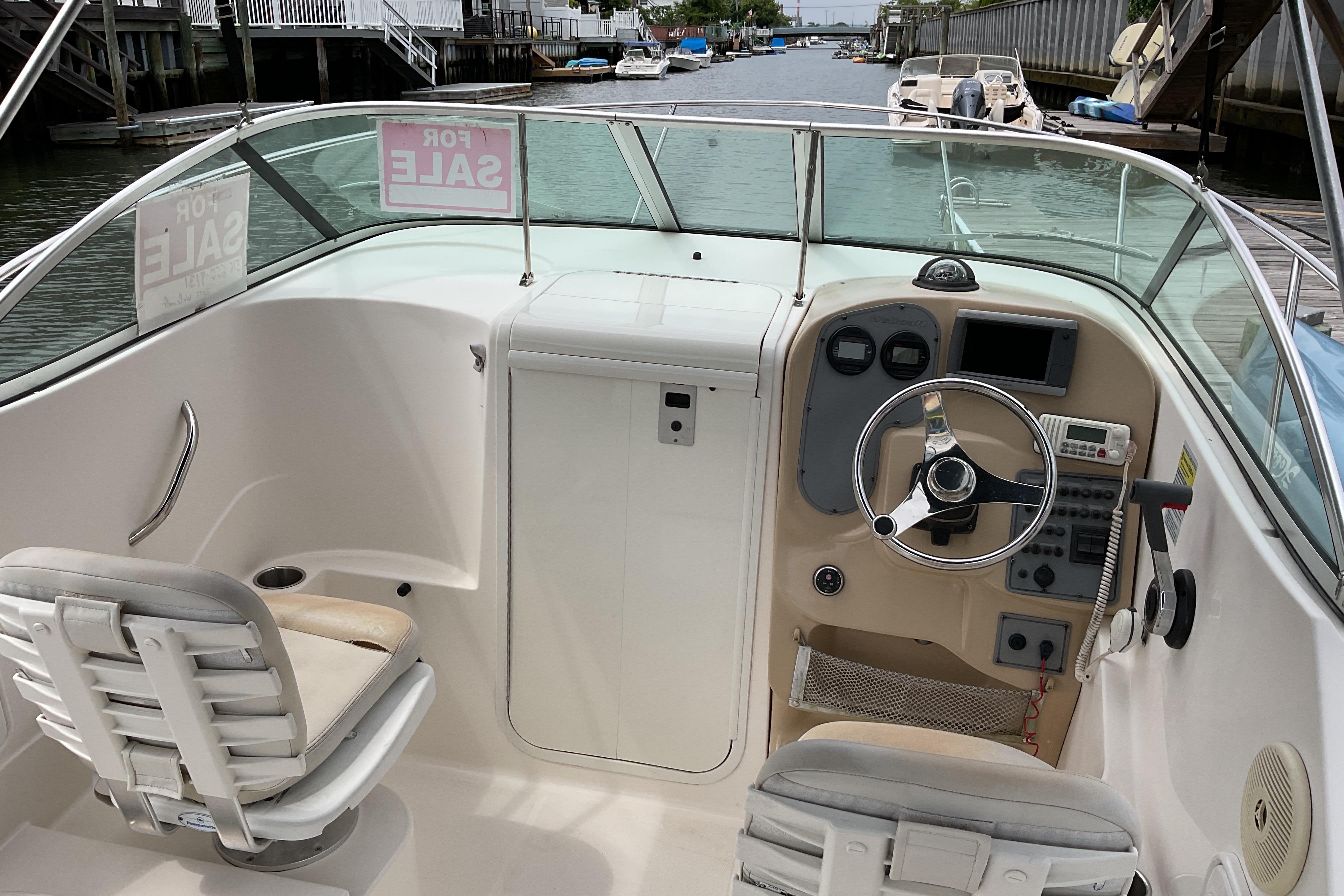2012 Wellcraft 232 Coastal boat interior with steering wheel, dashboard, and "For Sale" signs.
