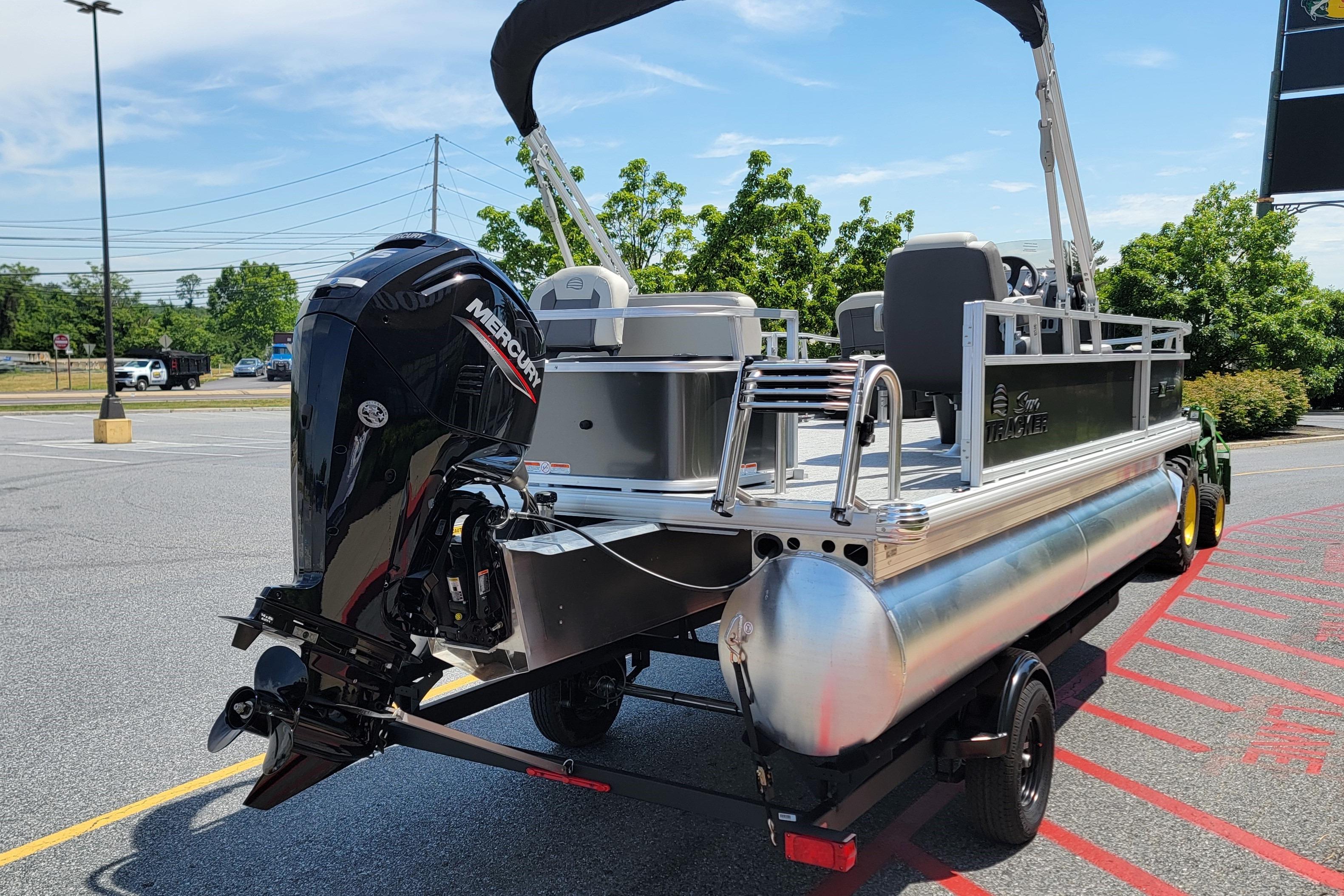 2026 Sun Tracker Bass Buggy 18 DLX pontoon boat with Mercury outboard motor in parking lot.