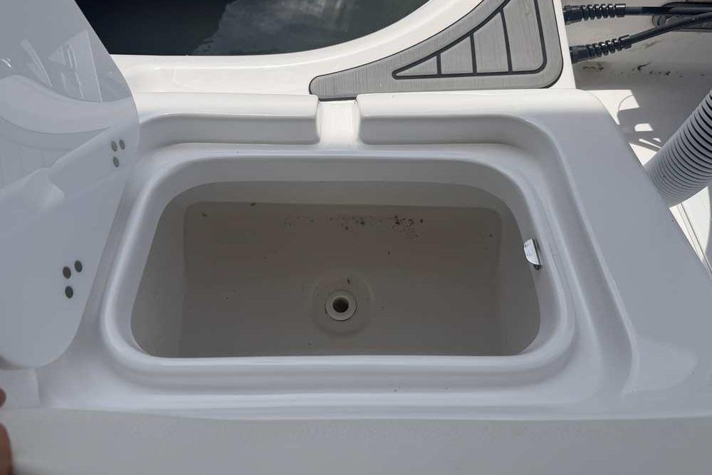 Open storage compartment on 2024 Tidewater 232 LXF boat, showcasing interior design.