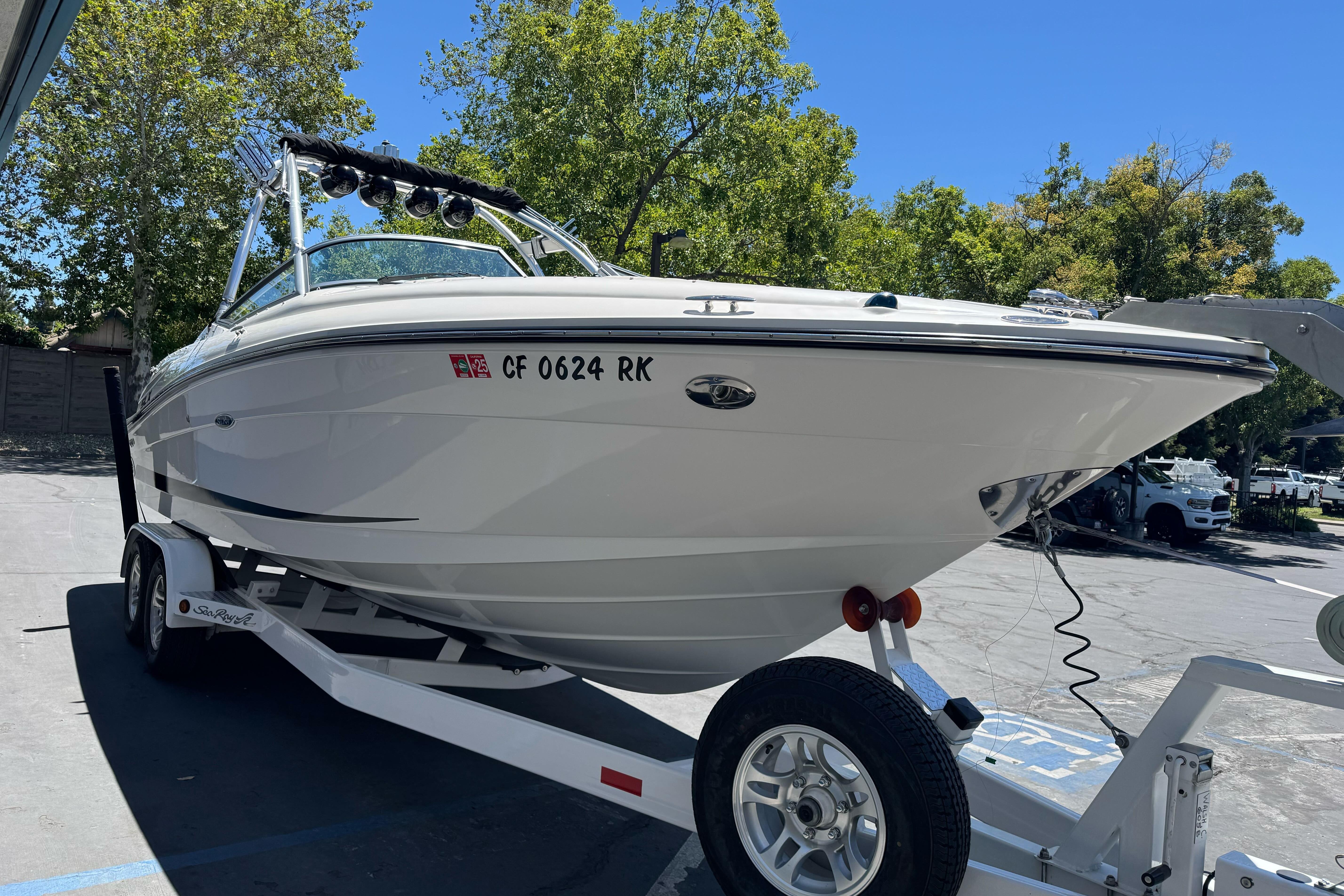 2007 Sea Ray SLX 250 boat on trailer, parked outdoors under clear blue sky.