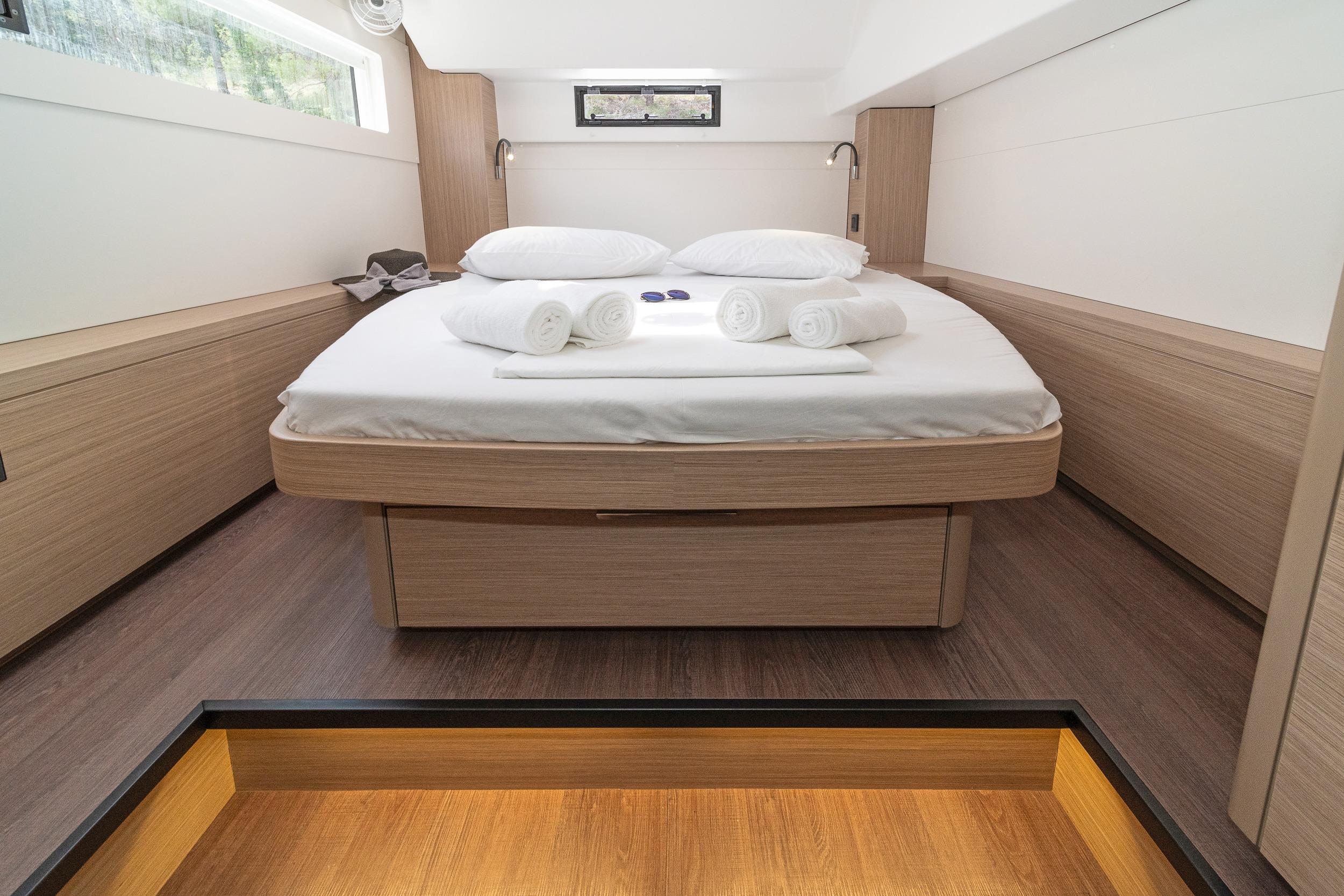Luxurious cabin interior of 2023 Lagoon 46 yacht with modern design and cozy bedding.
