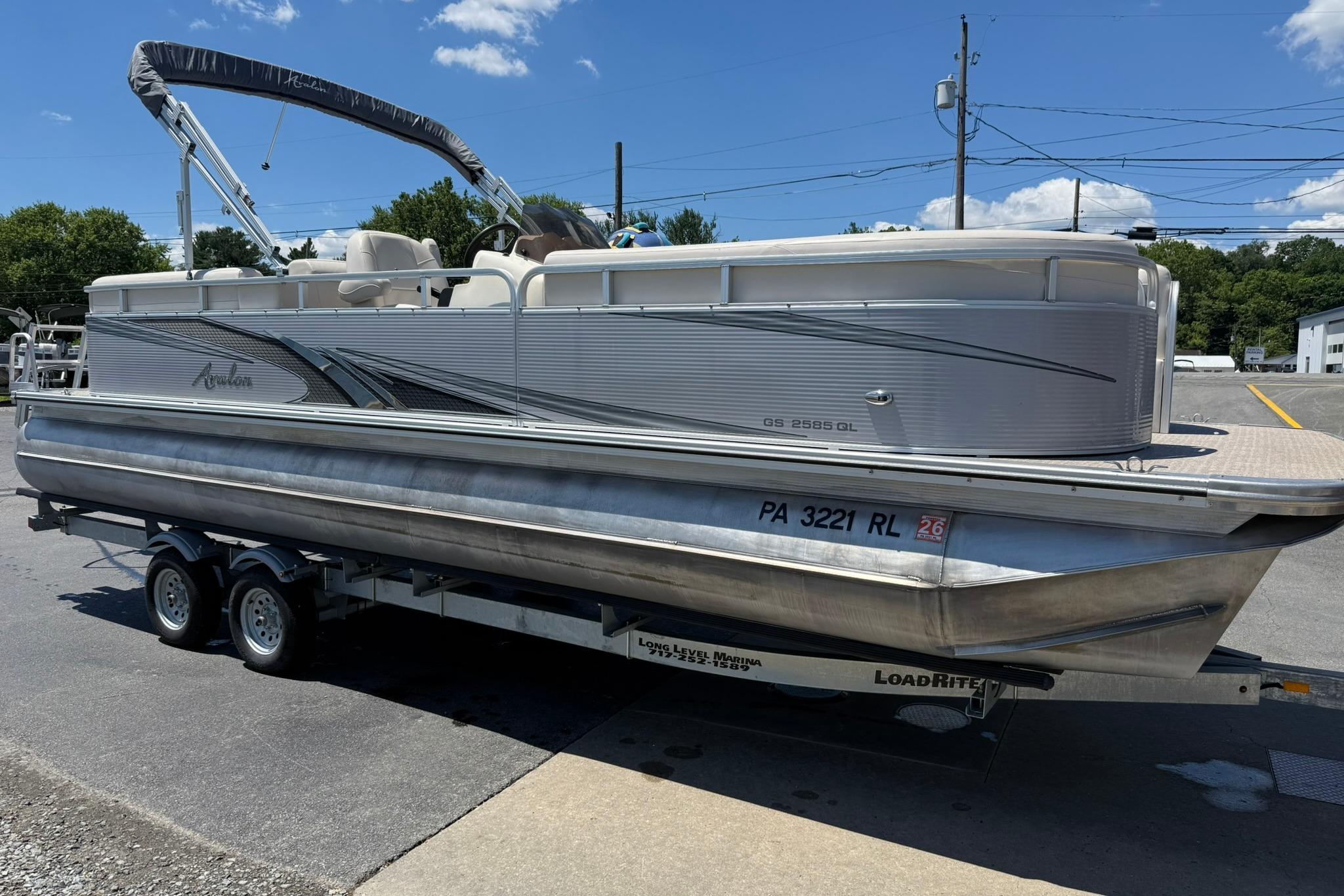 2019 Avalon GS Quad Lounge 25' pontoon boat on trailer, parked outdoors.