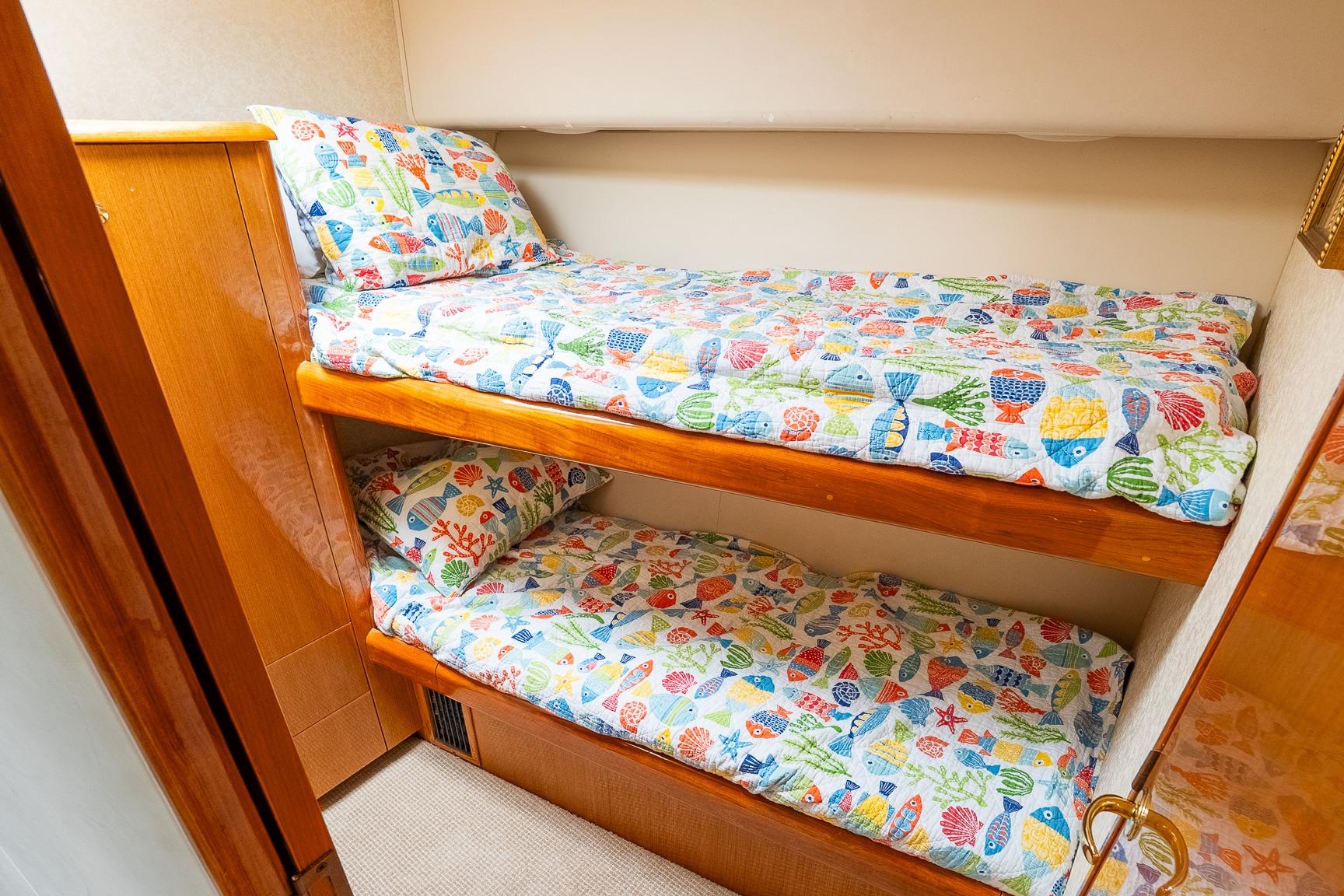 Bunk beds with colorful fish-themed bedding in 2002 Viking 61 Enclosed Bridge yacht.