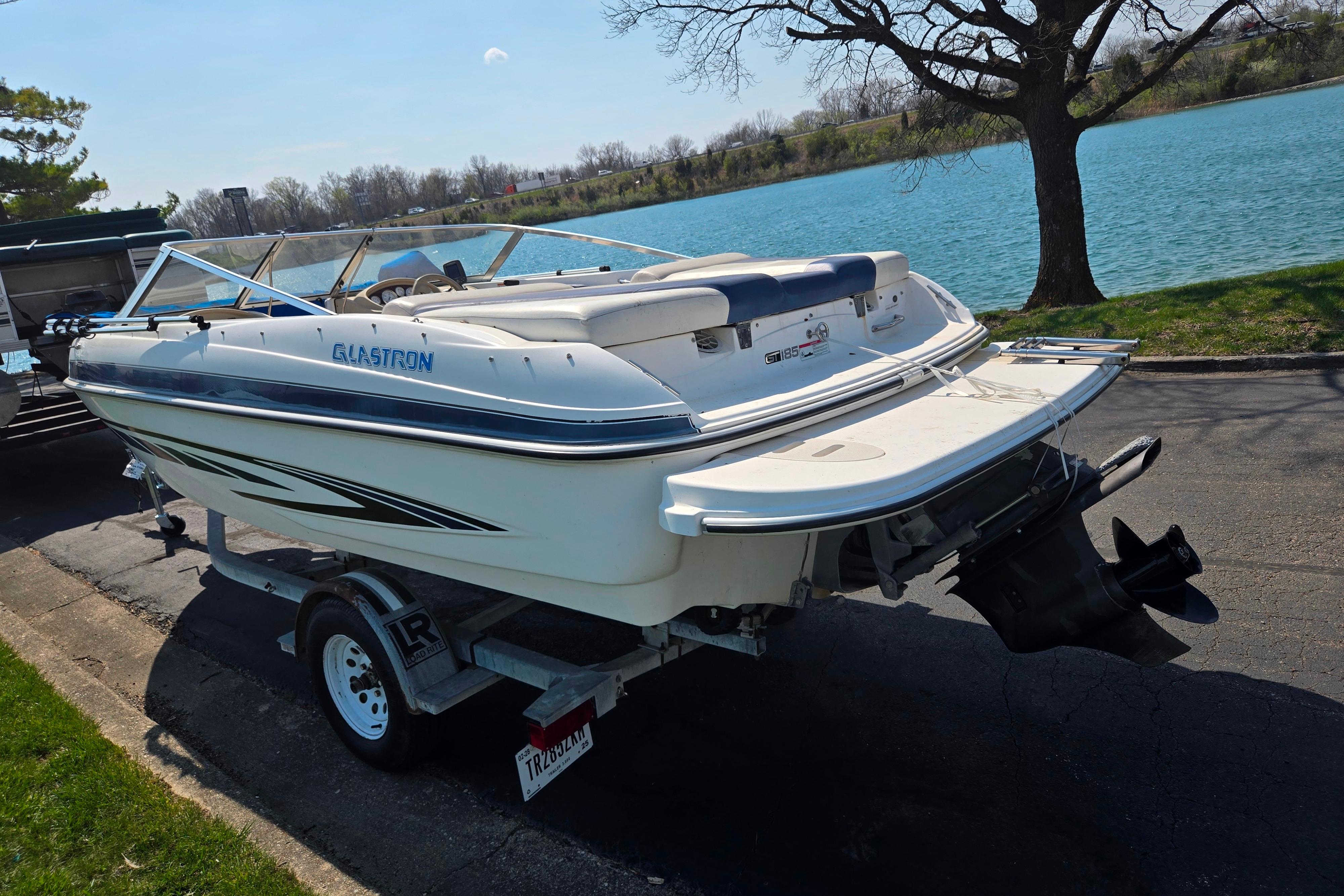 2007 Glastron GT 185 boat on trailer by a scenic lake.