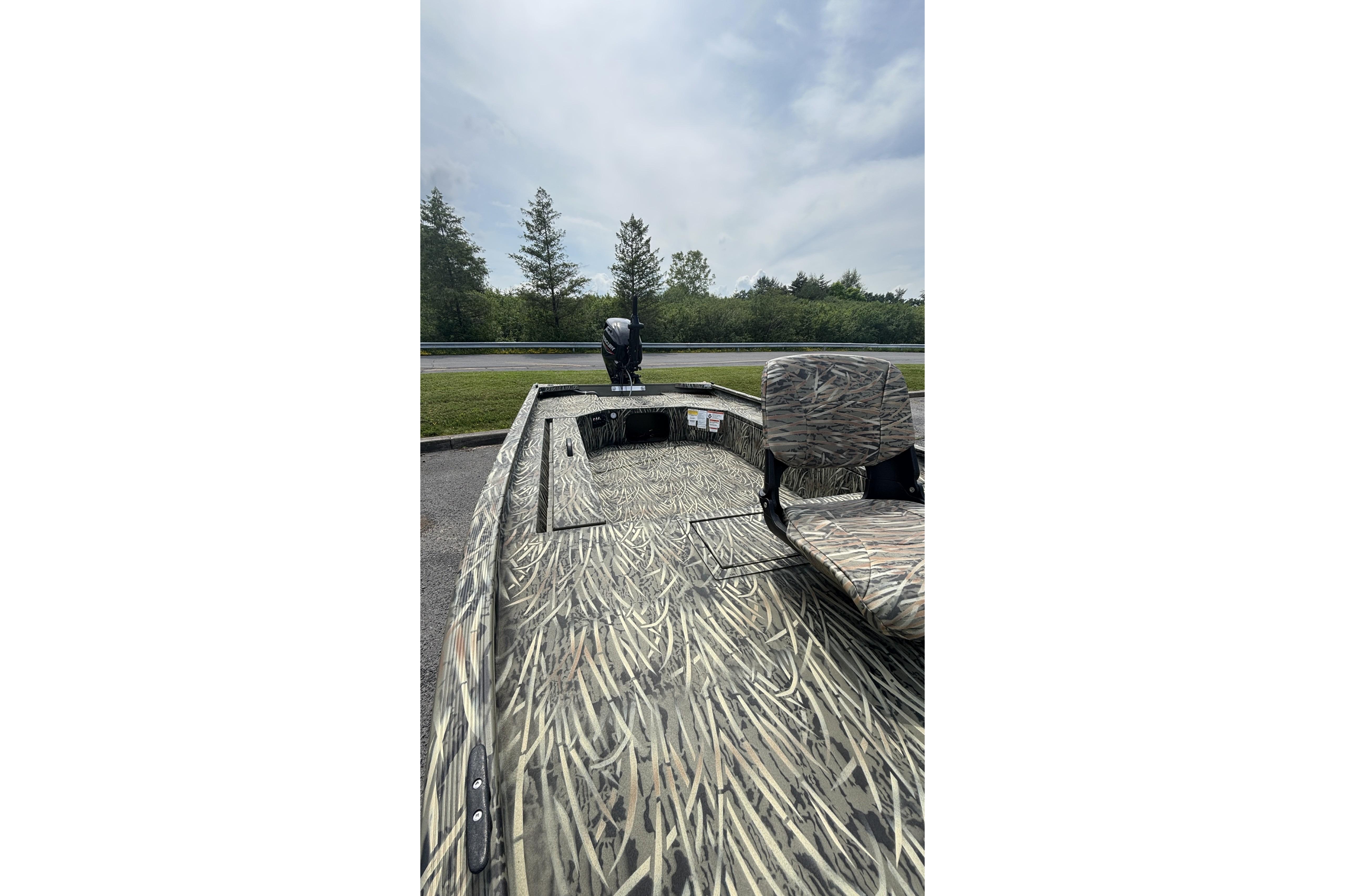 2026 Tracker Grizzly 1654 T Sportsman boat with camouflage design, parked outdoors.