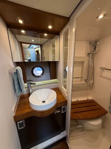 The image shows an elegant yacht bathroom with a sink, mirror, and shower.