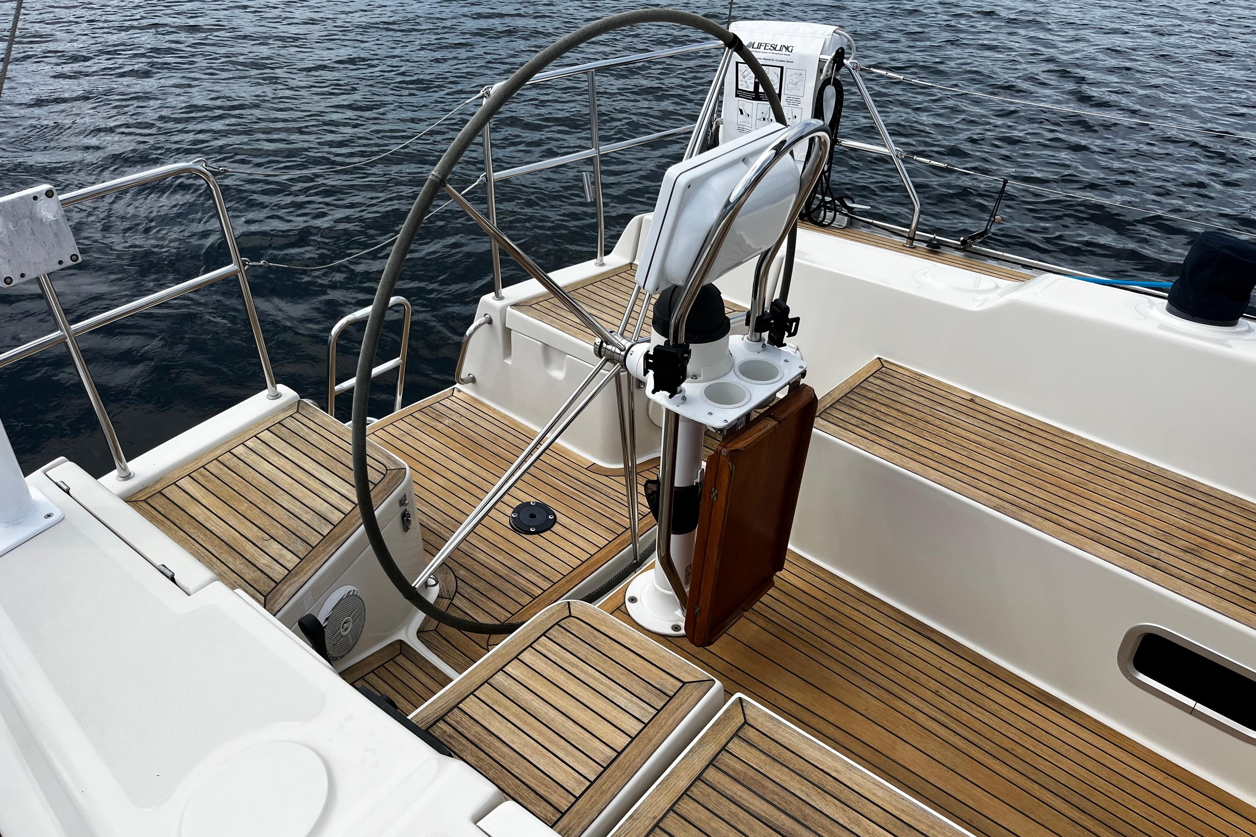 2004 Hanse 411 sailboat cockpit with wooden deck and steering wheel on calm water.
