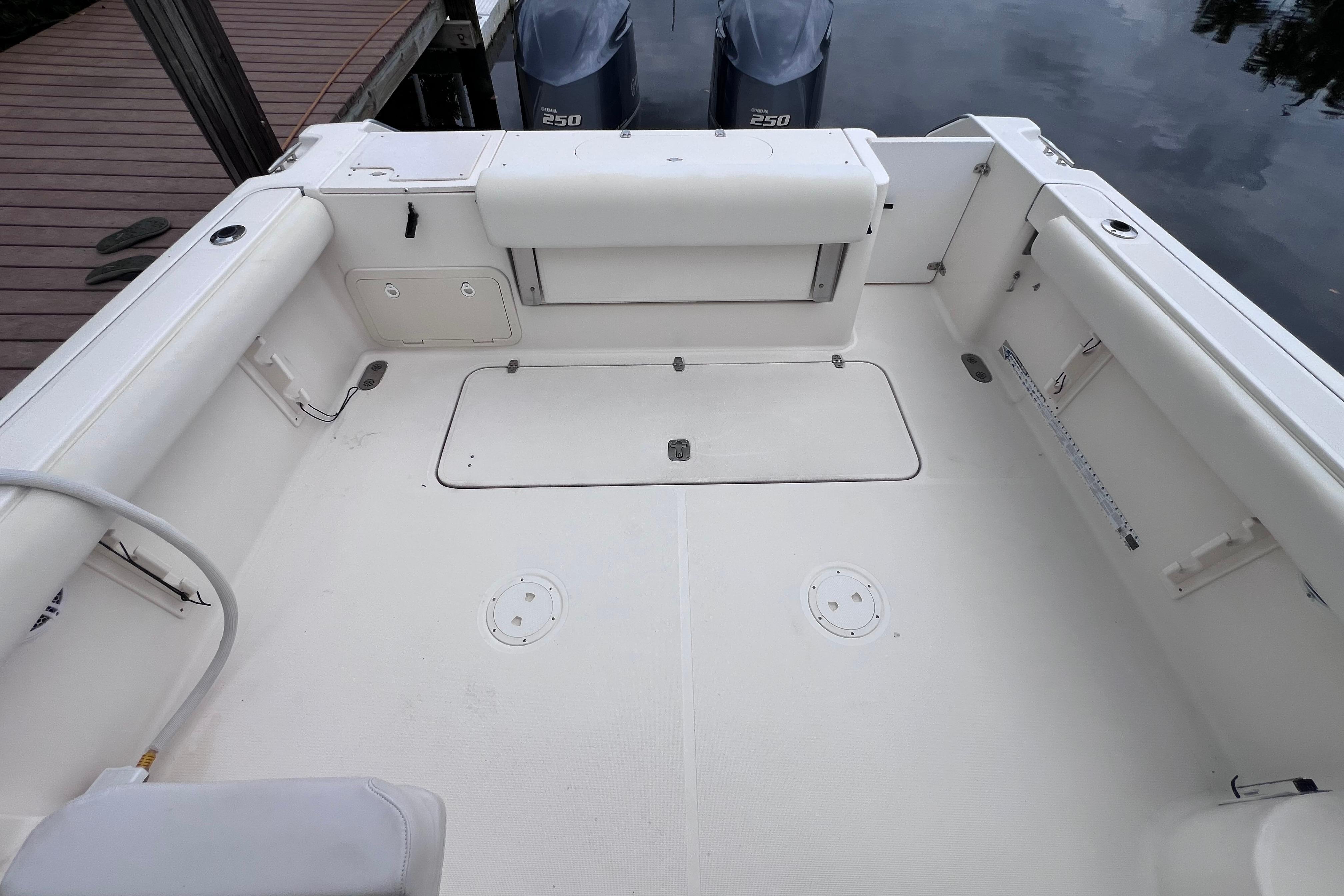 2005 Pursuit 3070 Offshore boat deck with twin 250 engines, docked by wooden pier.