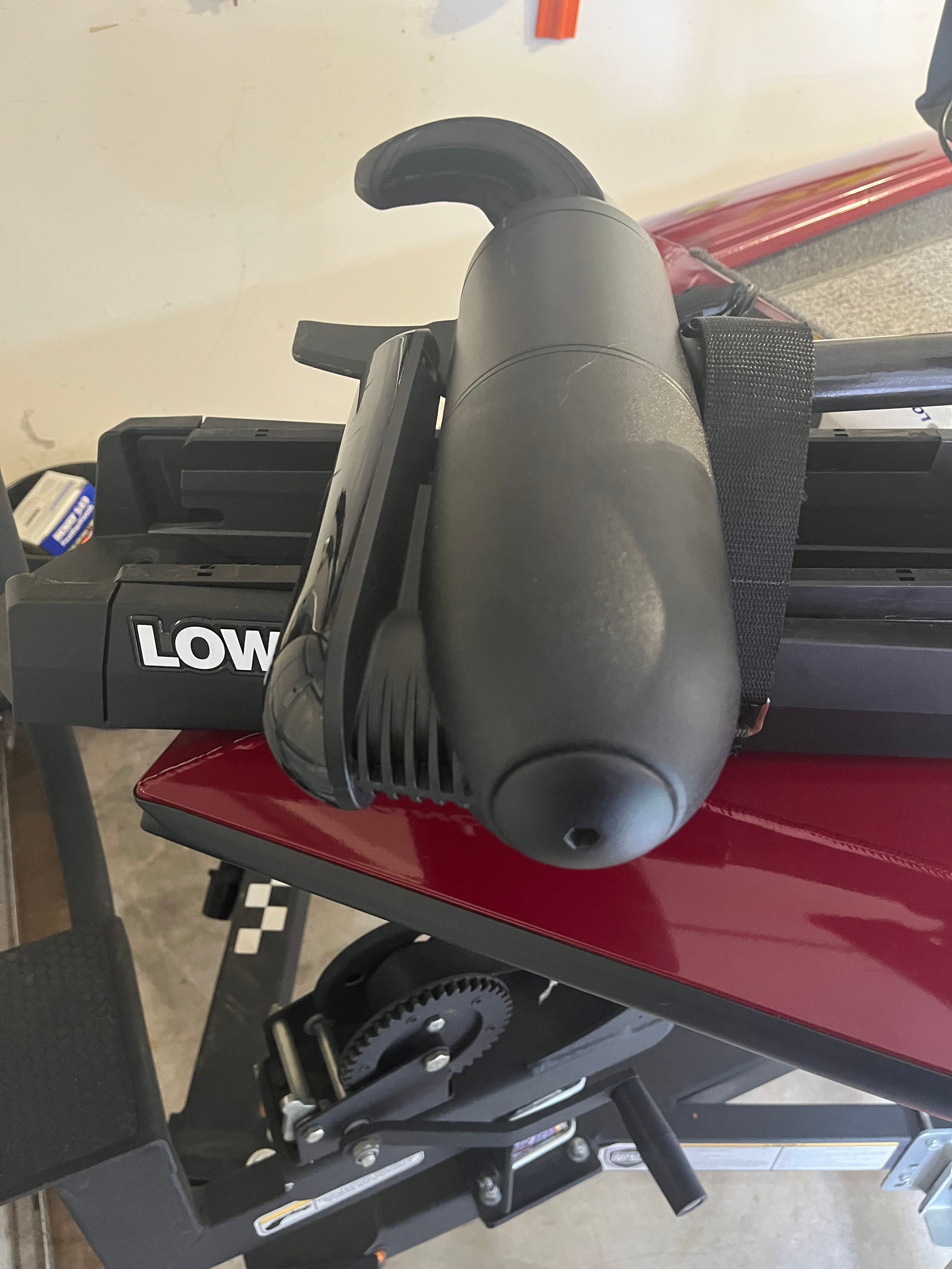 Close-up of a boat steering system with a black handle and red background.
