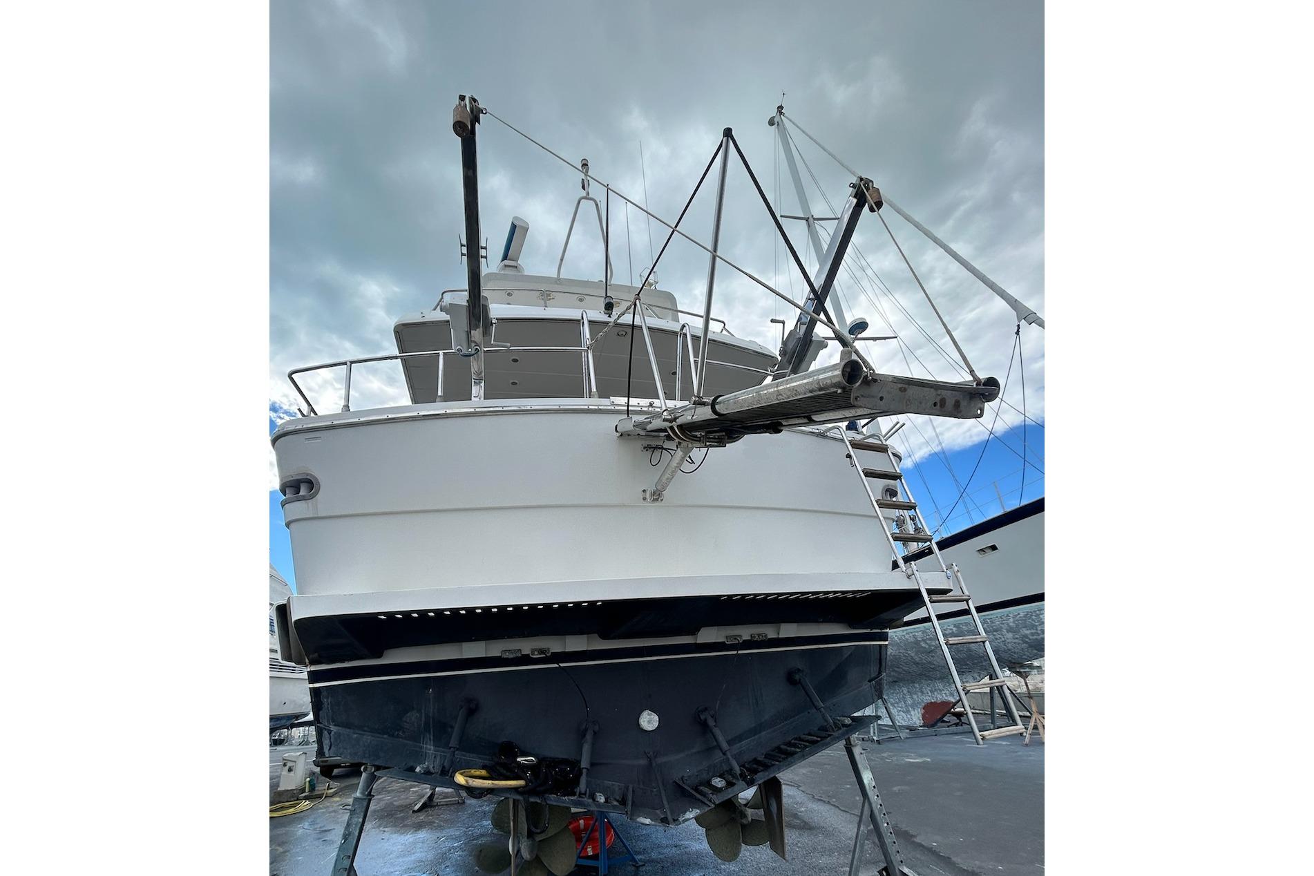 1990 San Lorenzo 57 yacht on dry dock, viewed from the stern under cloudy skies.