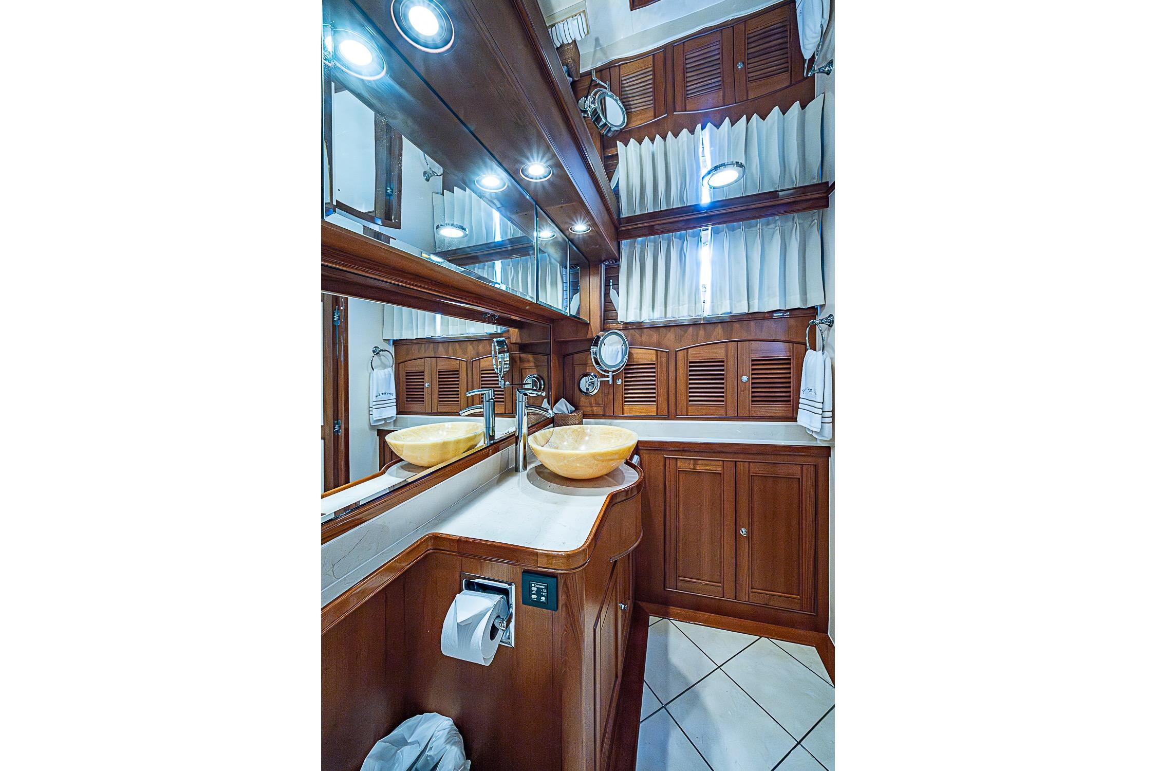 Luxurious bathroom in 2014 Marlow 80 Explorer yacht with wooden cabinetry and vessel sinks.