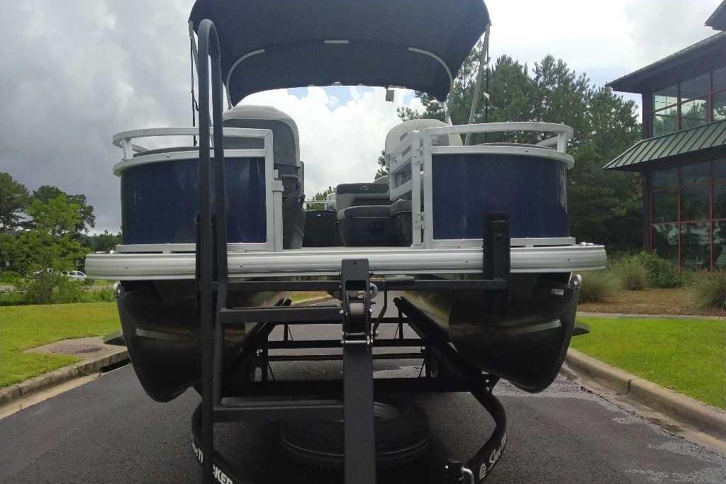2026 Sun Tracker Bass Buggy 18 DLX pontoon boat on trailer, parked outdoors.