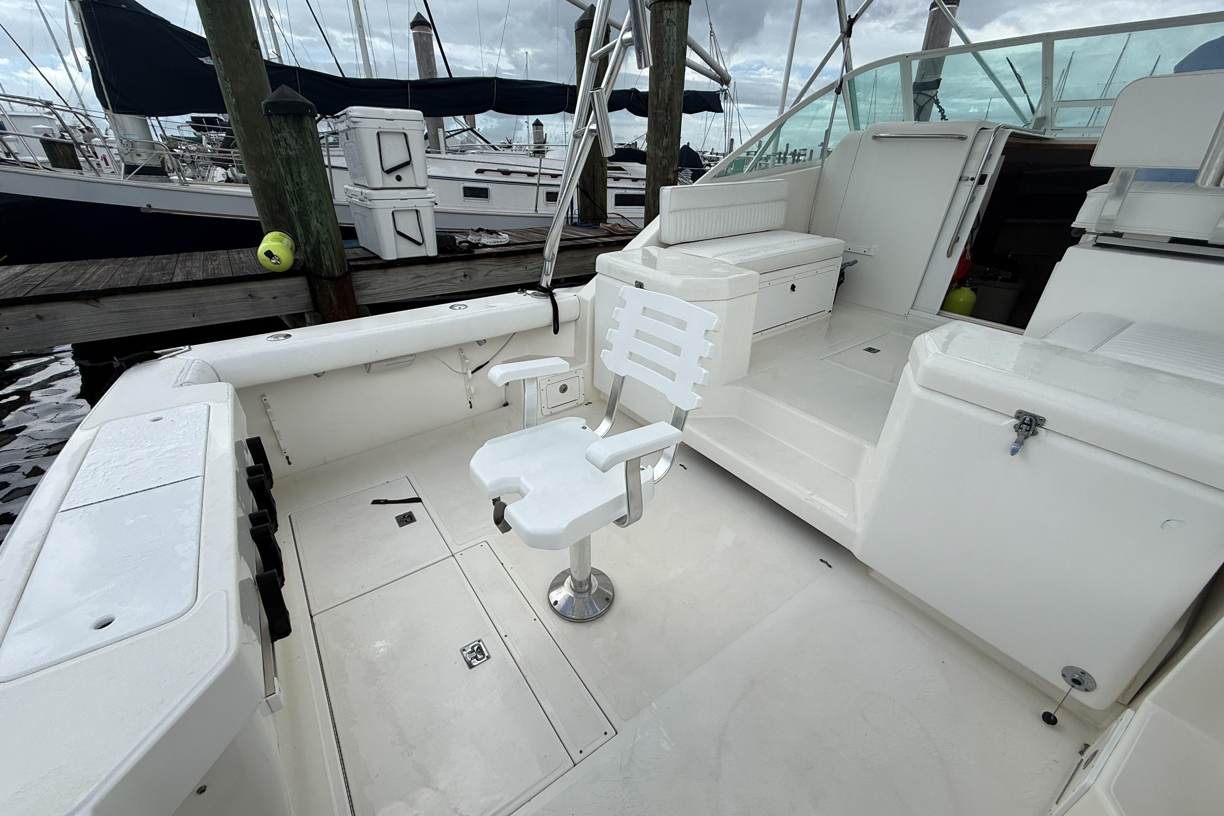 1998 Cabo 31 Express boat interior with seating and fishing chair at dock.