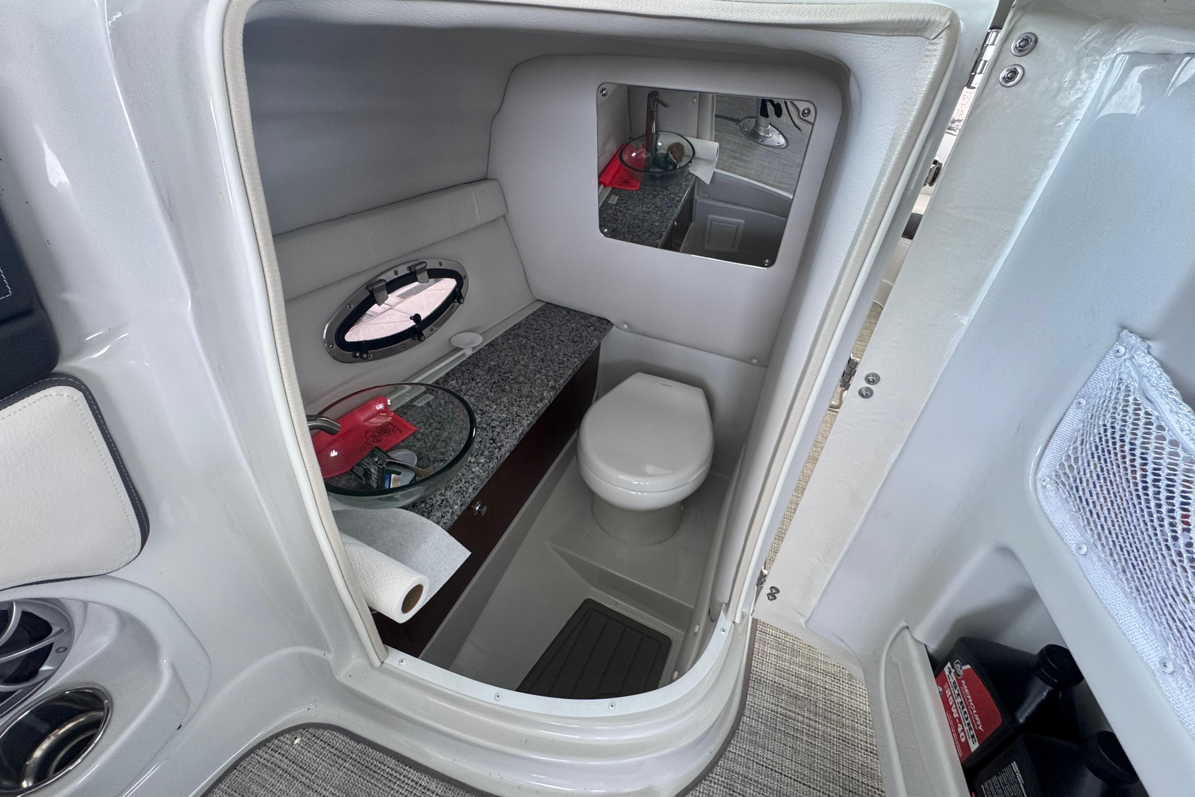 2022 Crownline 265 SS boat interior bathroom with toilet, mirror, and storage.