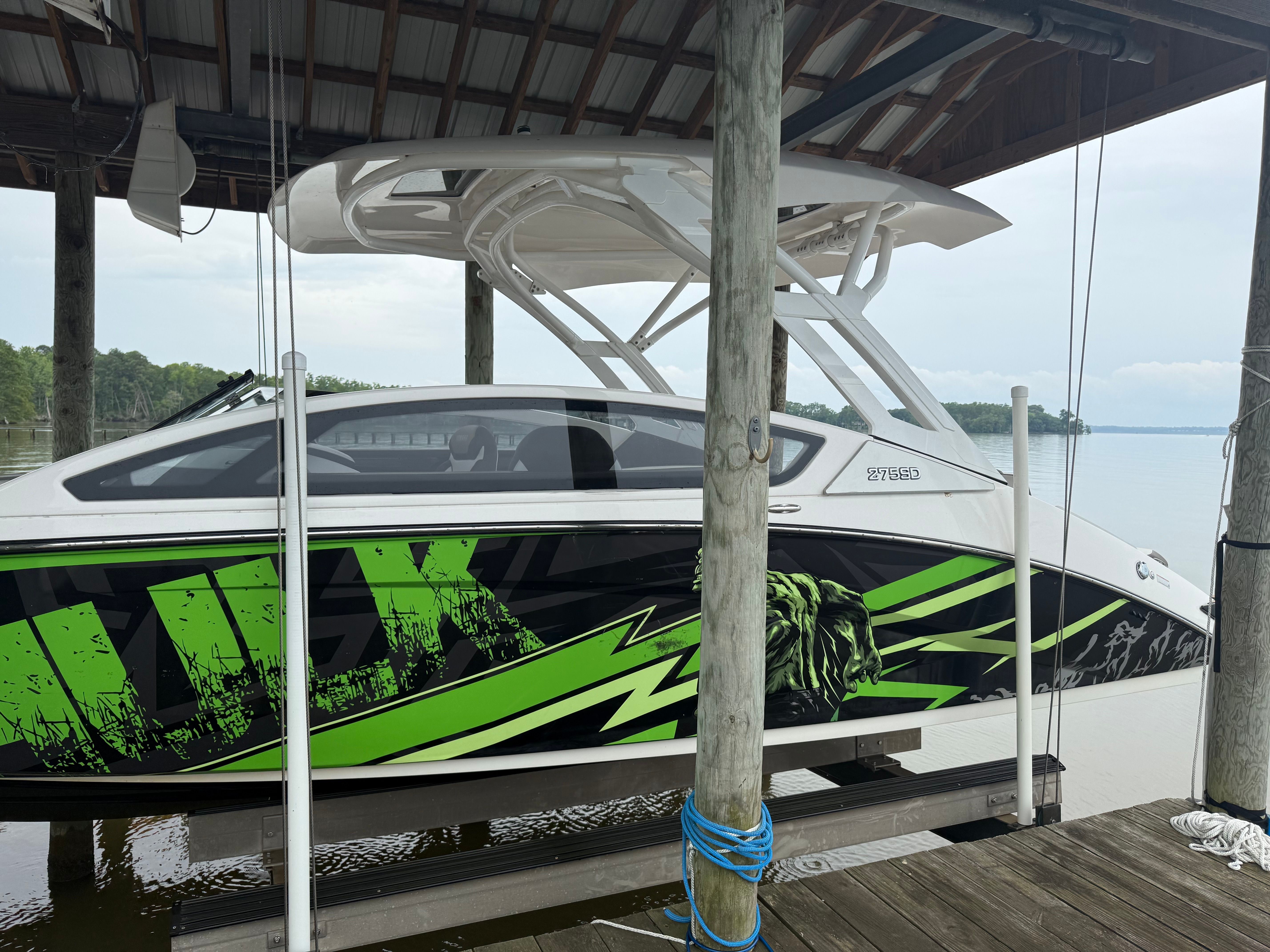 A 2022 Yamaha 275SD boat with striking green design docked under a covered pier.