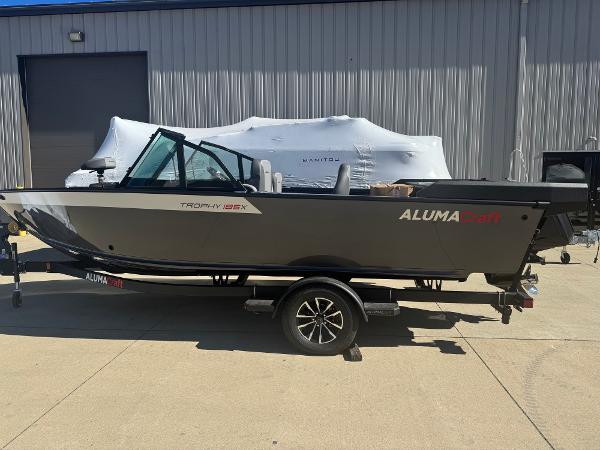 2025 Alumacraft Trophy 185X SC Rotax S boat on trailer, parked outdoors.