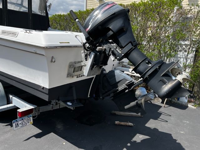 A 1998 Sport-Craft 252 Sport Fish boat with an outboard motor parked on a trailer.