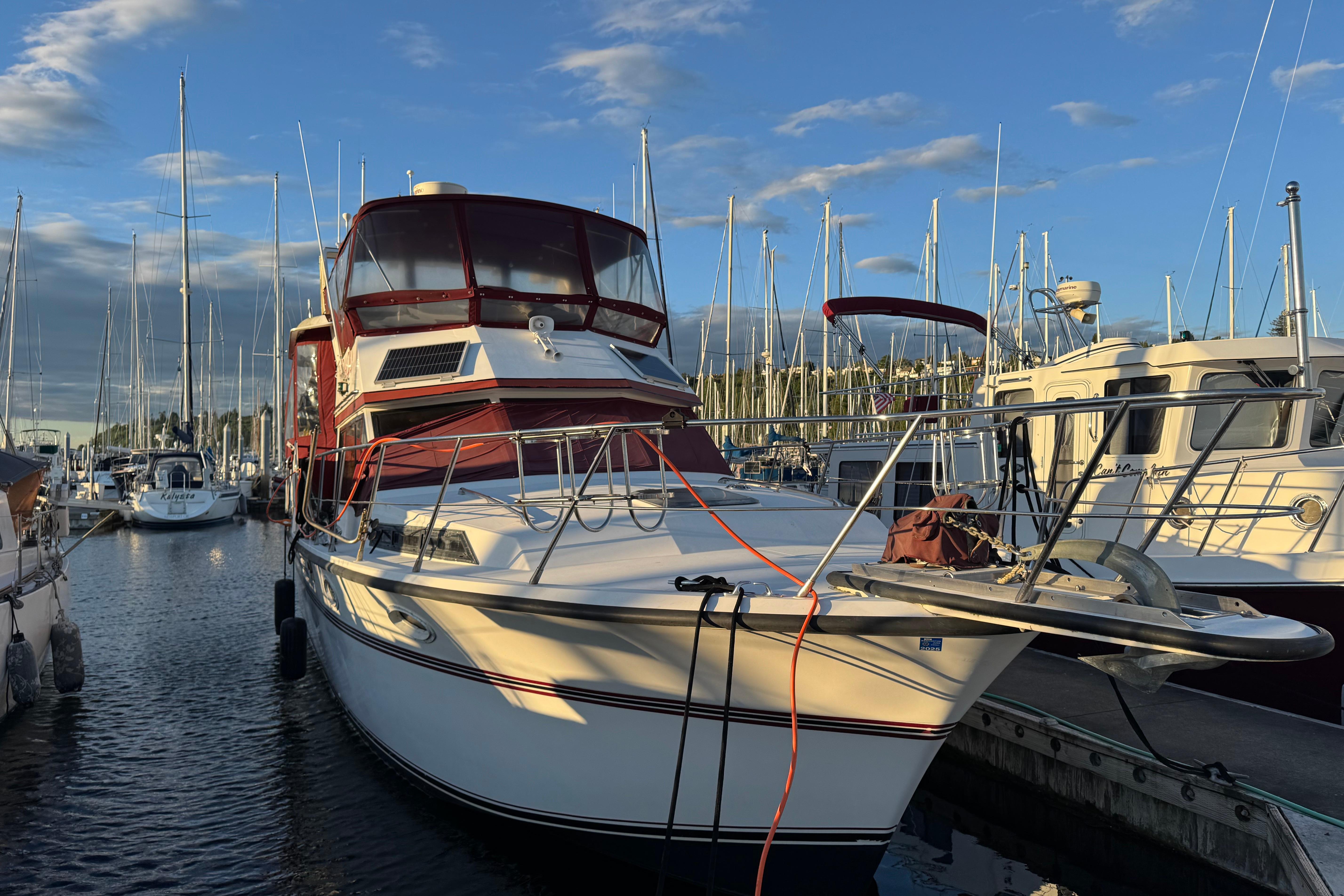 1987 President 37 yacht docked at marina, surrounded by sailboats under a blue sky.