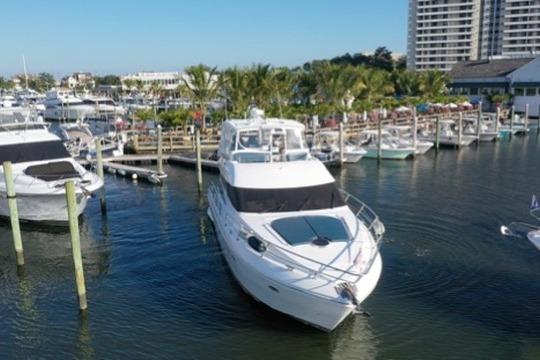 2005 Neptunus 56 Flybridge yacht docked in a marina with palm trees.