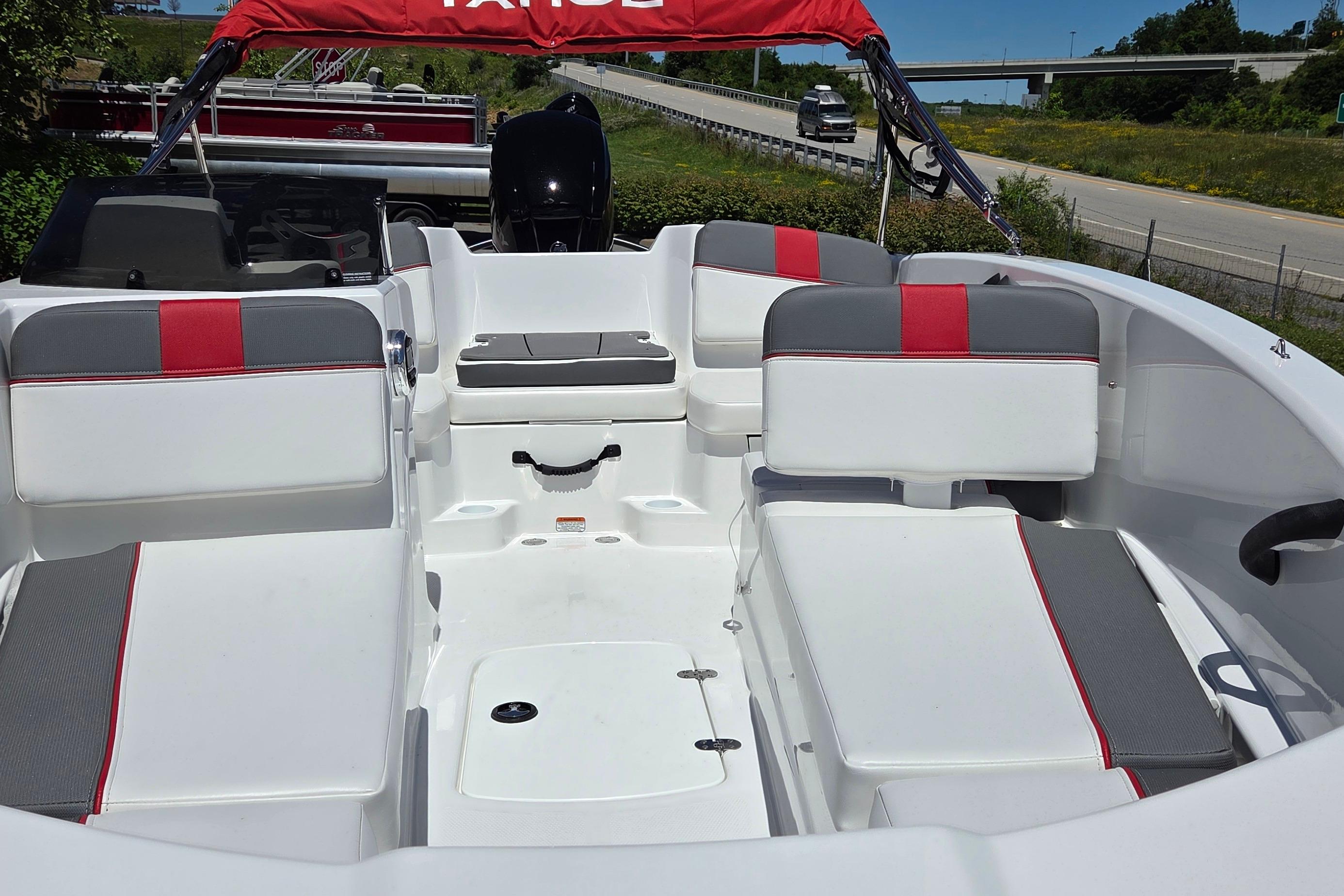 2026 Tahoe T16 boat interior with white and red seating, parked near a highway.