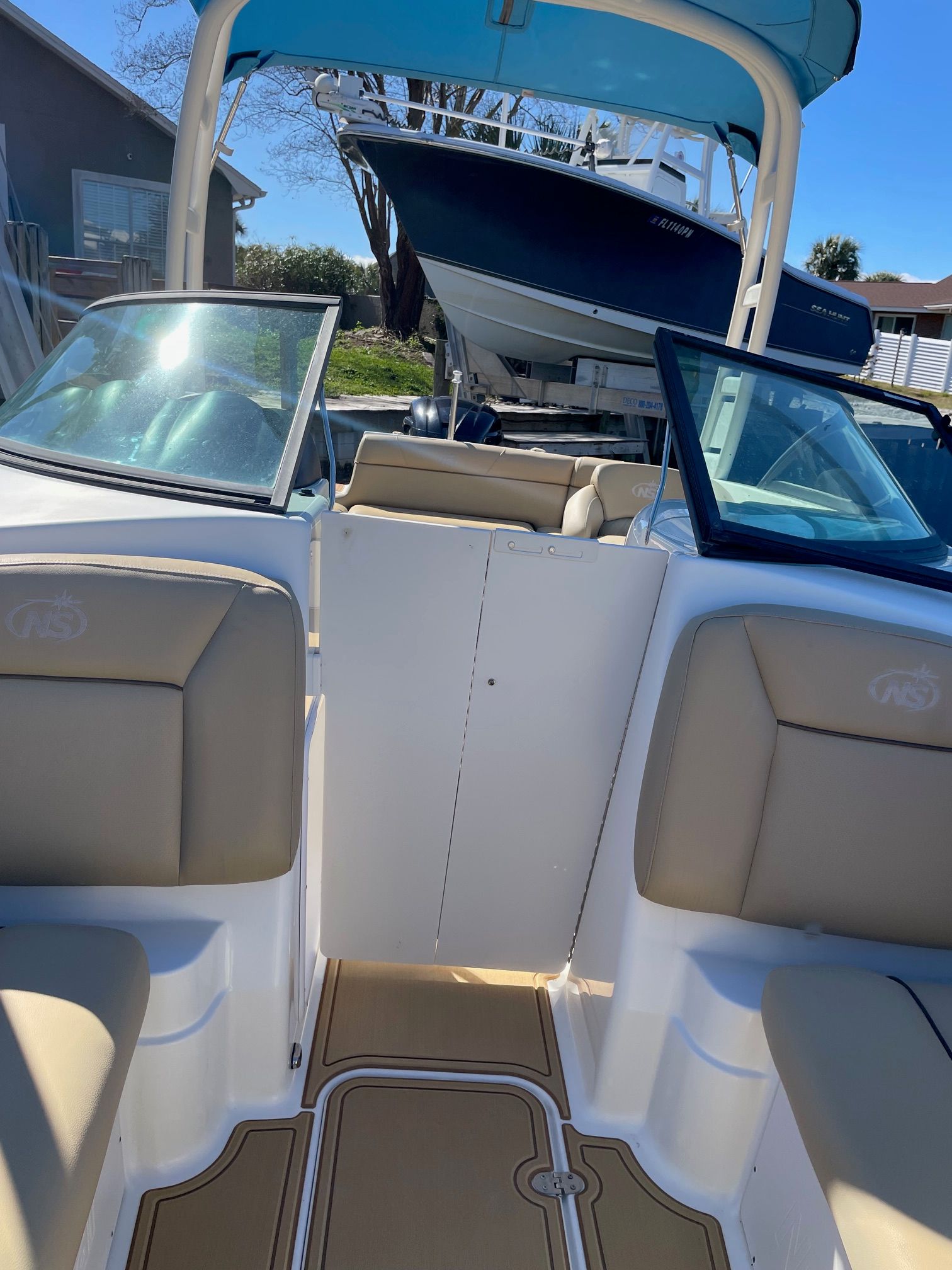 NauticStar 243DC Sport Deck 2019 with beige interior and blue accents, parked outdoors.