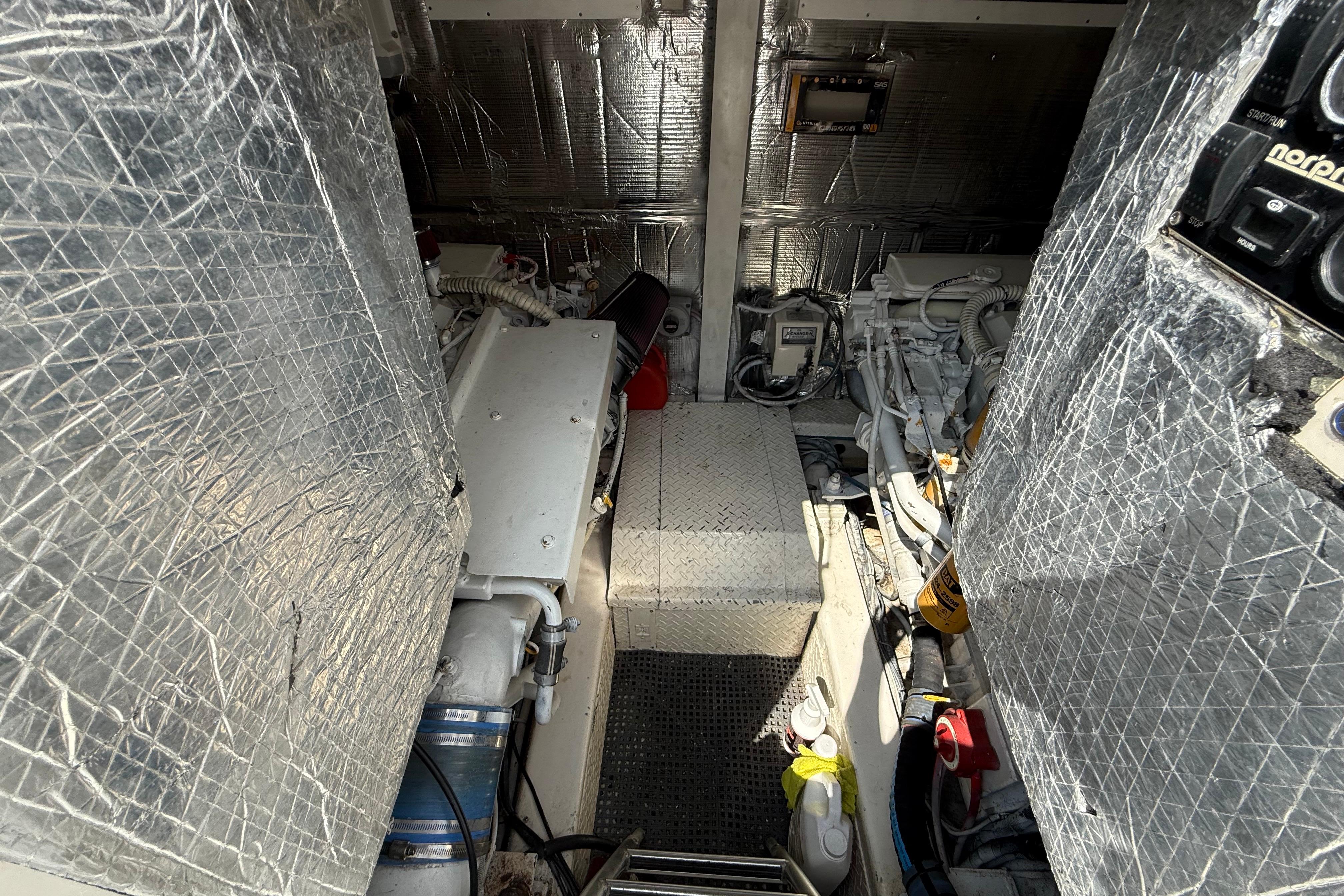 Engine room of 1999 Ocean Yachts 40 Express, featuring insulated walls and mechanical components.