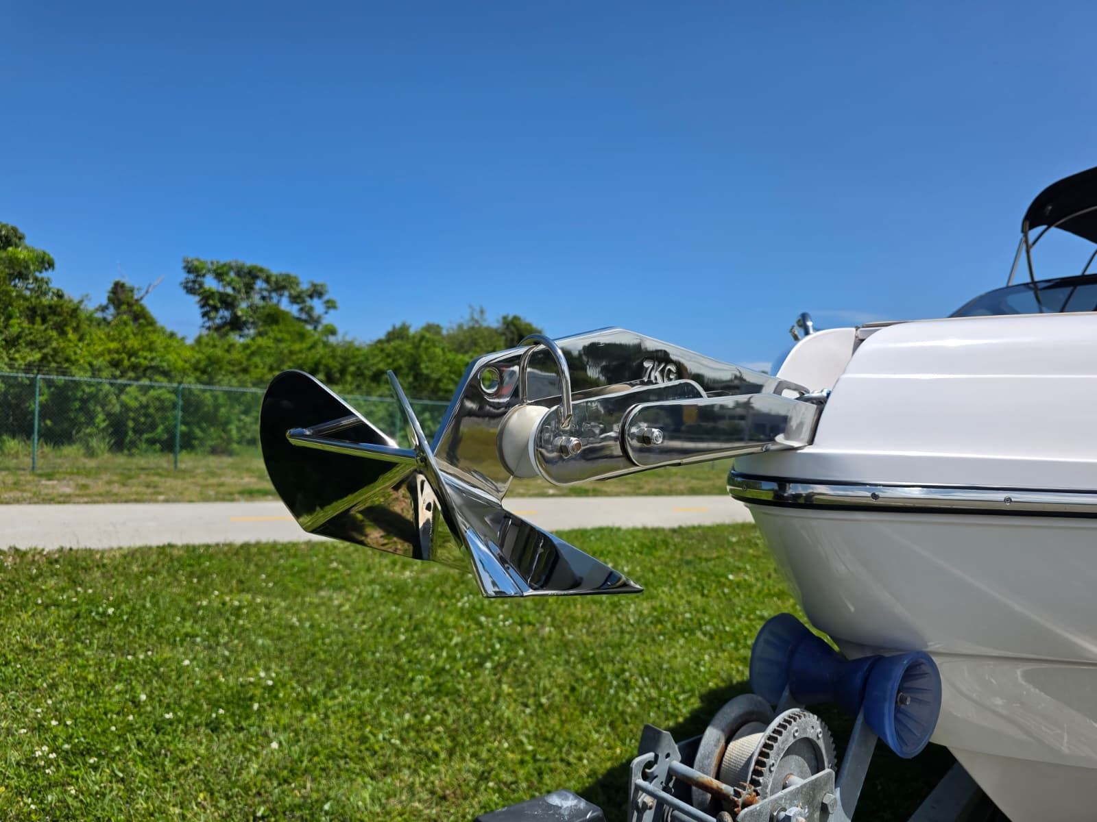 A shiny propeller on a boat on a trailer, surrounded by grass and trees.