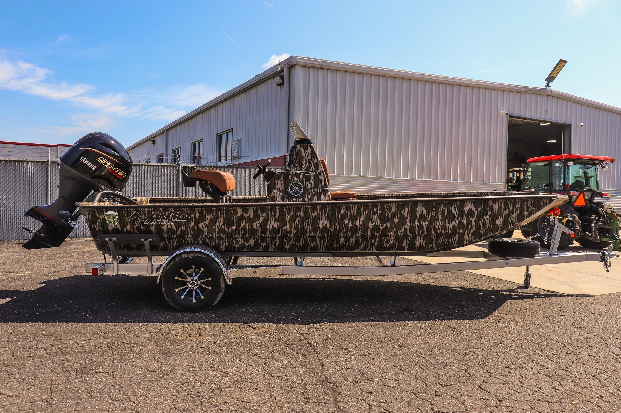 An Avid 20 Rogue CC boat on a trailer in front of a building.