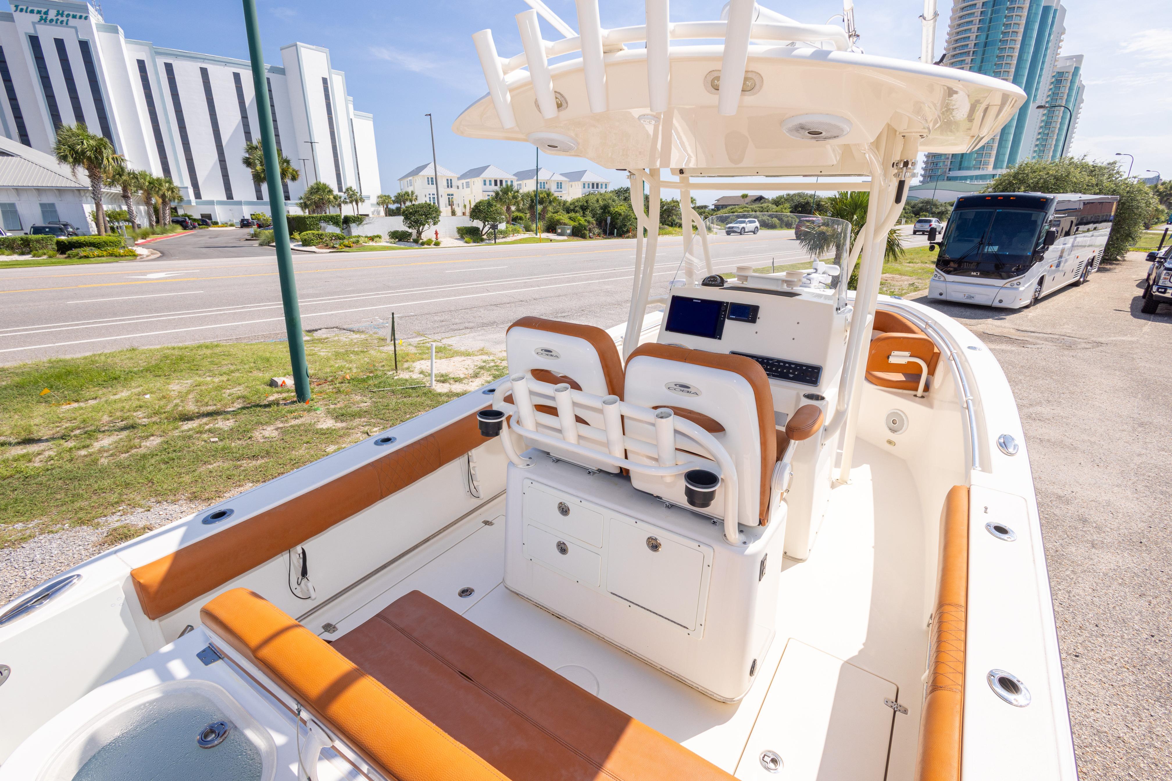 2017 Cobia 261 Center Console boat with tan seating, parked near a road and buildings.