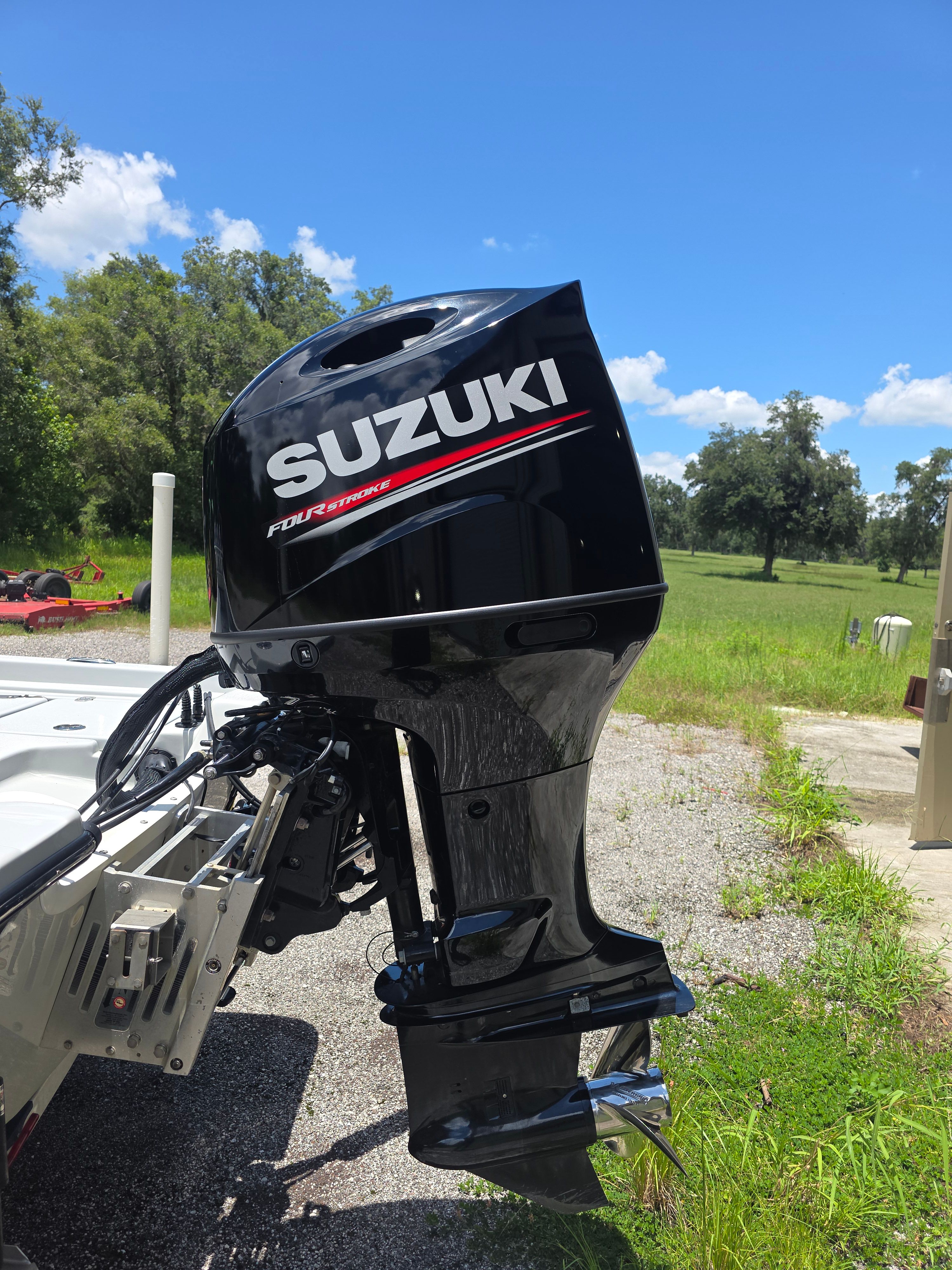 Outboard motor of a boat with Suzuki logo, on a trailer outdoors.