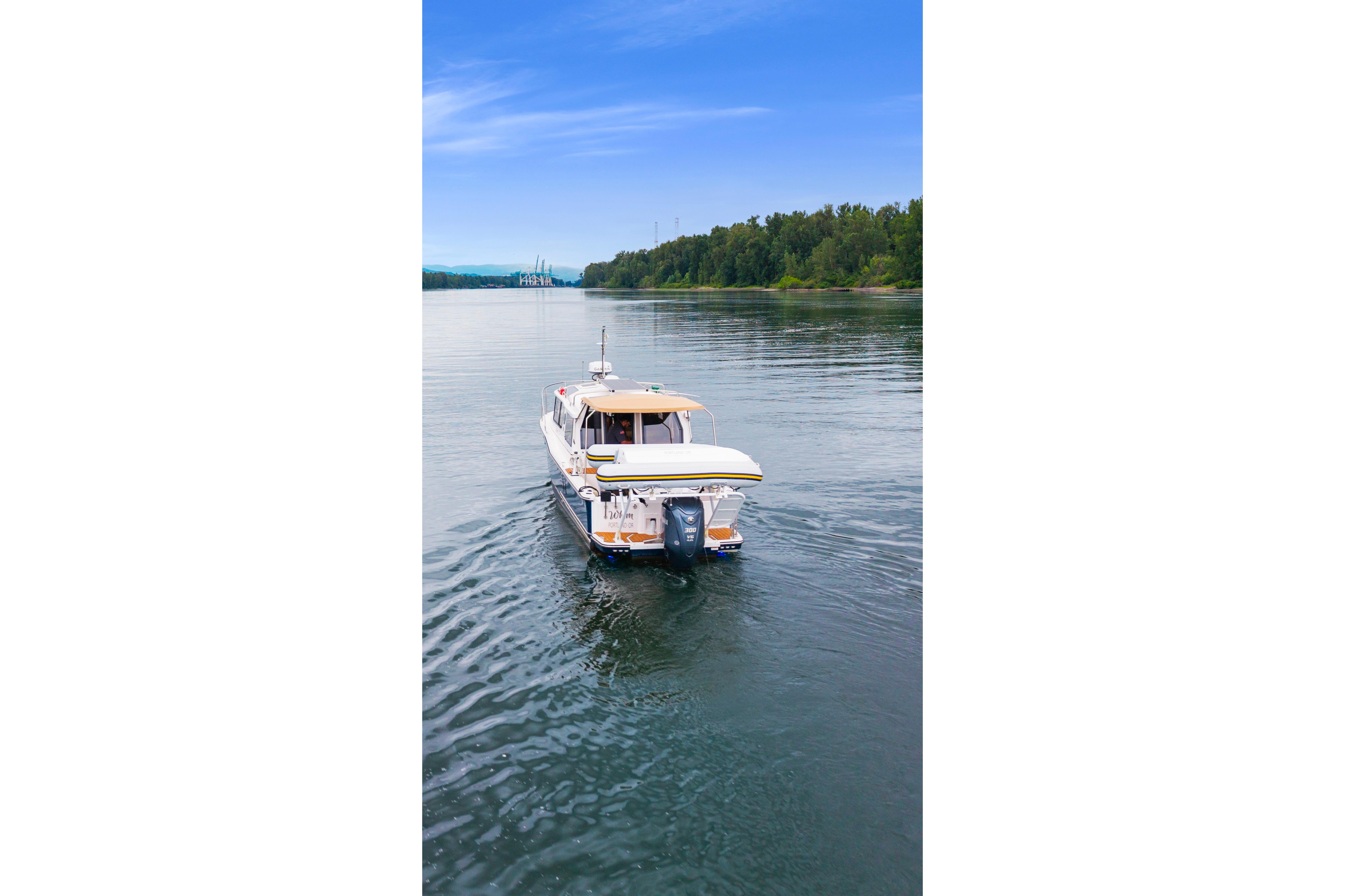 2022 Ranger Tugs R-27 cruising on a serene river under a clear blue sky.