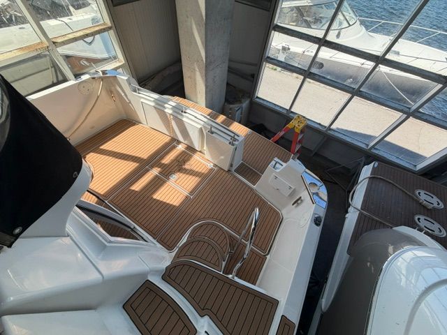 The image shows the cockpit of a 2005 Carver 44 Cockpit Motor Yacht. It features an elegant teak deck and is docked in a marina.