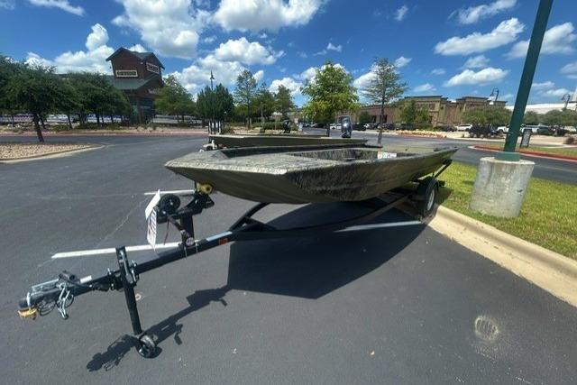 2026 Tracker Grizzly 1754 Utility boat on trailer in parking lot under blue sky.