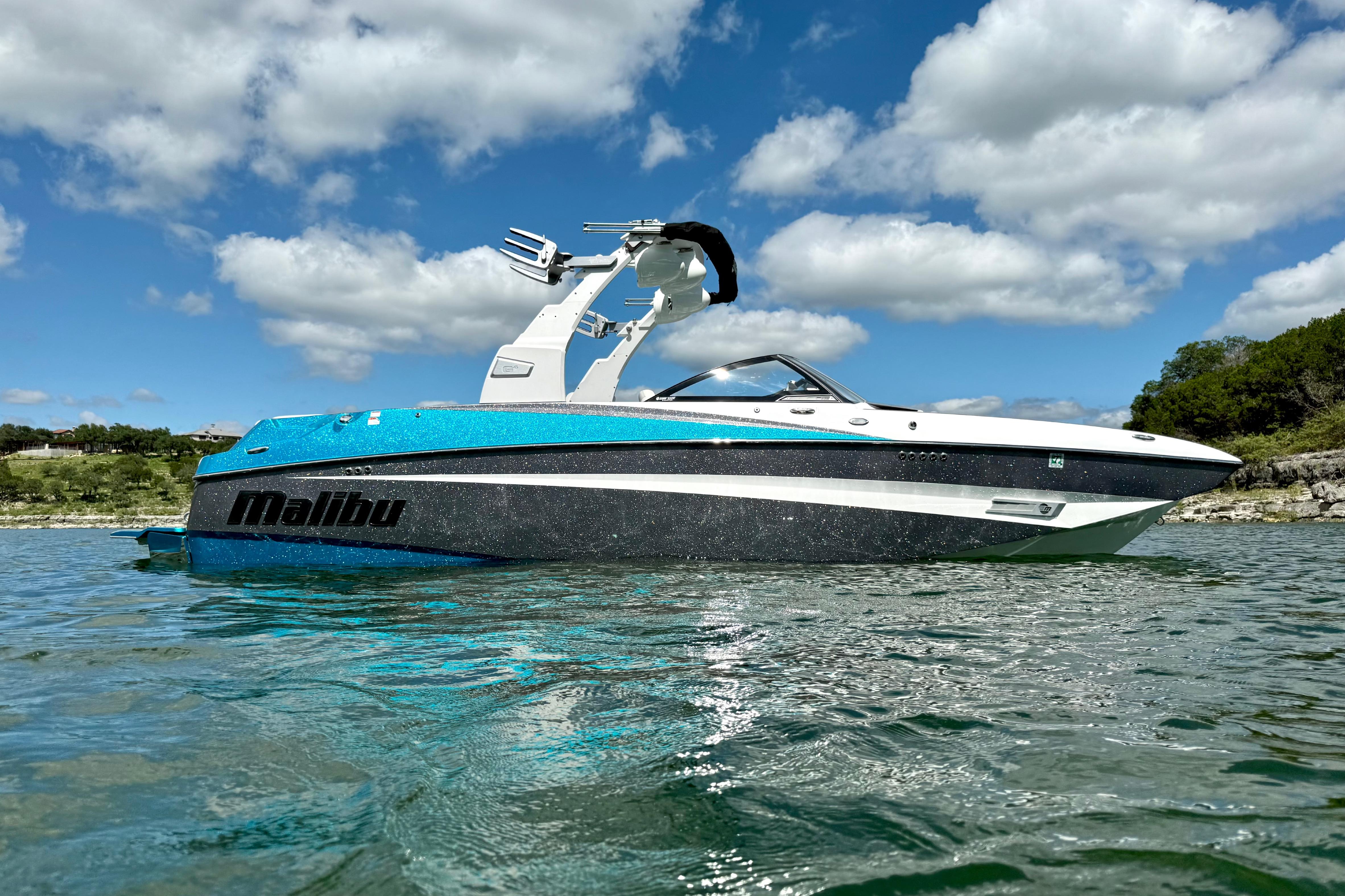 2017 Malibu M235 boat on water under blue sky with clouds.