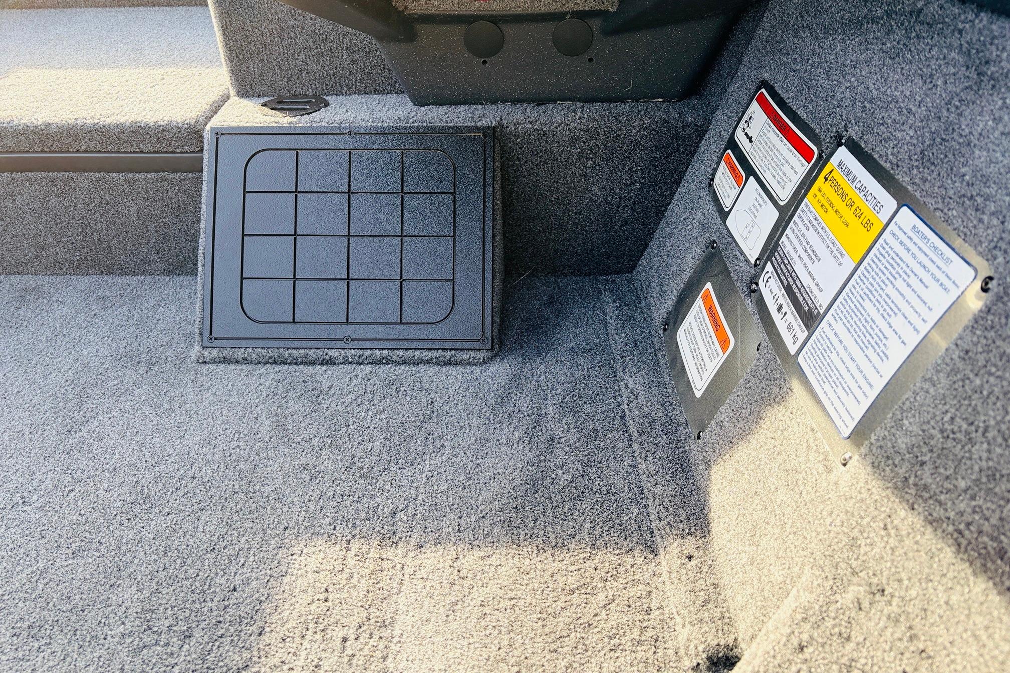 Interior of 2025 Tracker Savage 215 boat with safety labels and storage compartment.