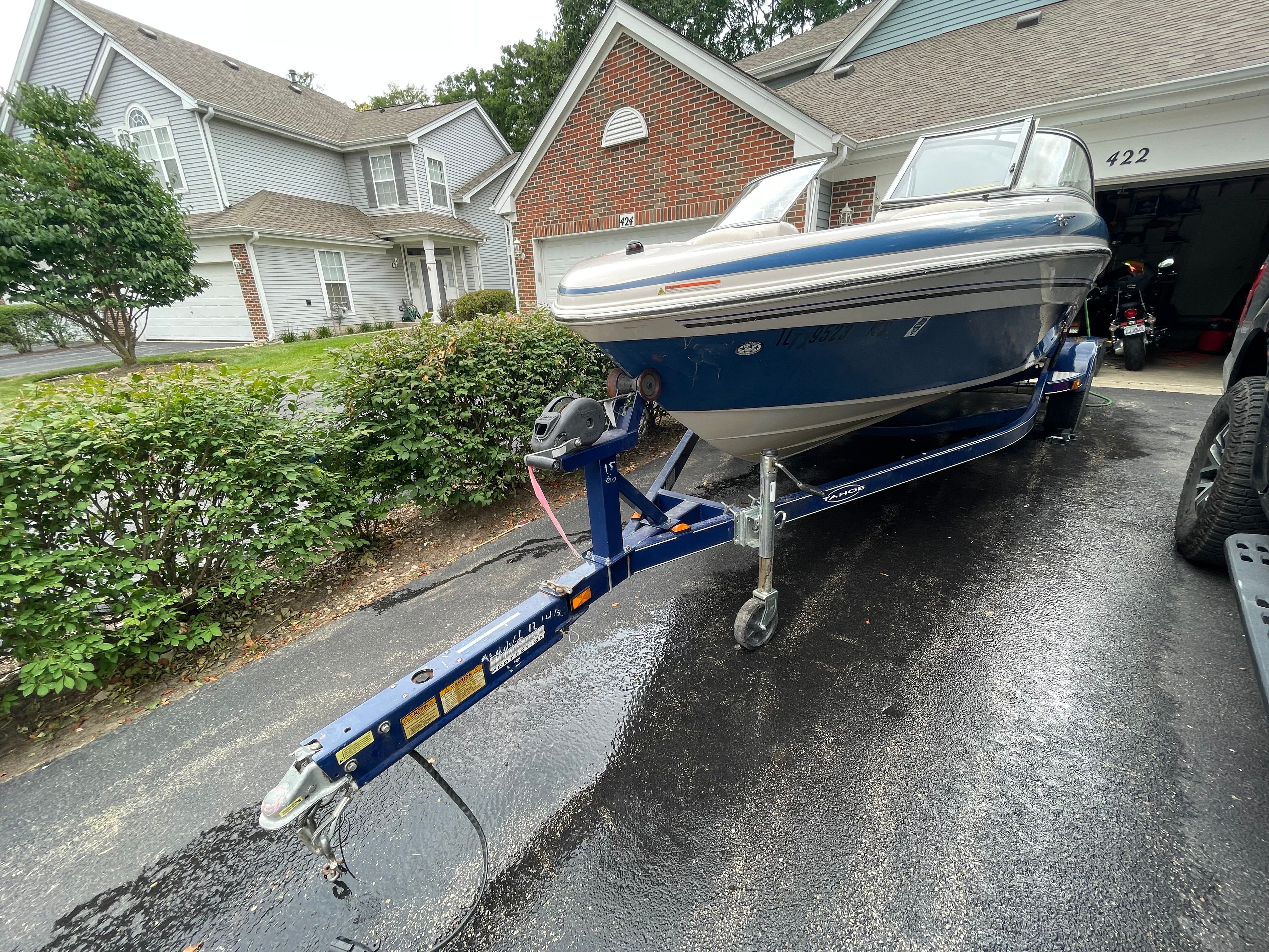 A blue 2005 Tahoe Q6 Sport boat on a trailer in a driveway.