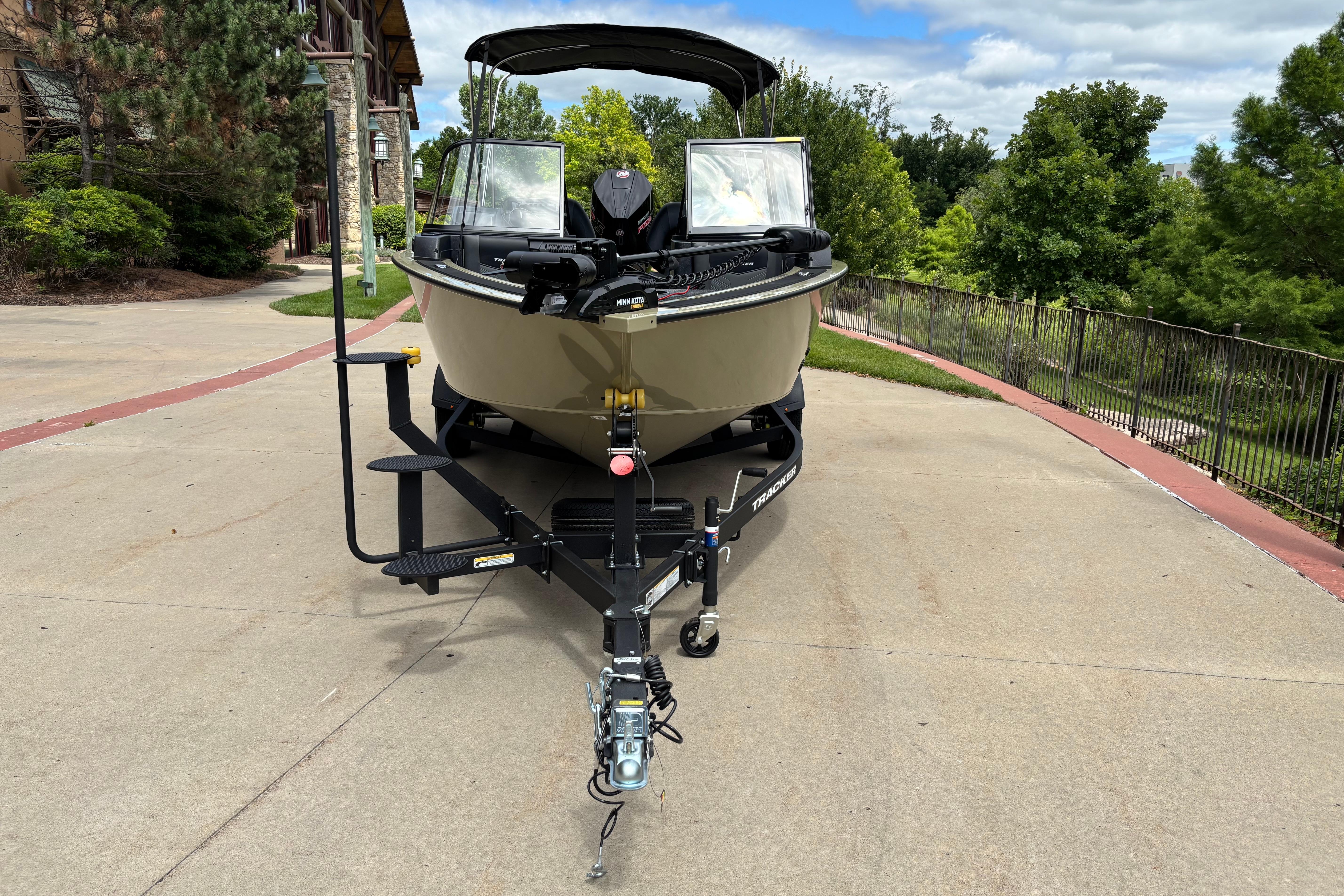 2026 Tracker Targa V-18 Combo boat on trailer, parked on a driveway with lush greenery.