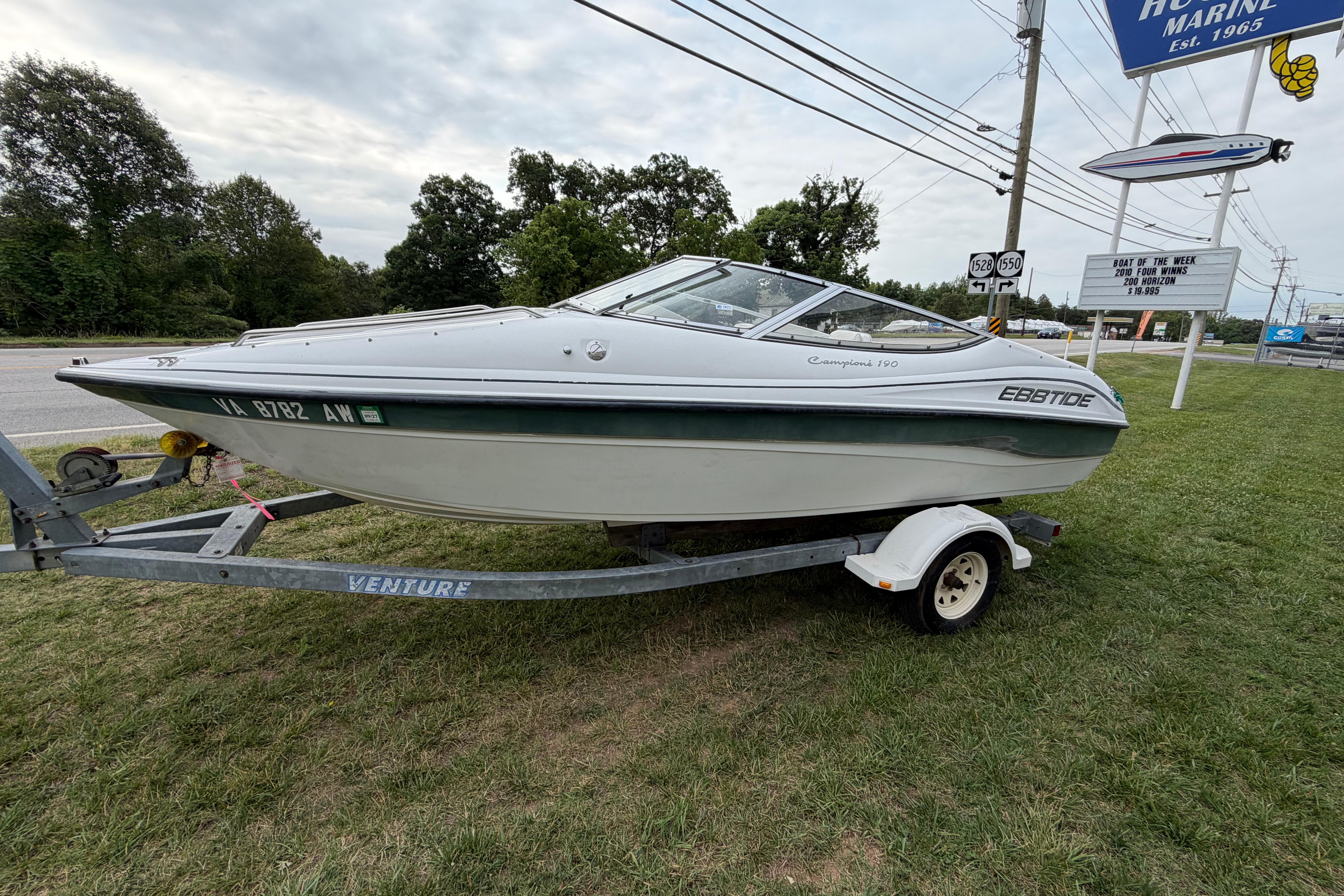 2001 Ebbtide Campione 190 boat on trailer, displayed outdoors near a marine dealership.