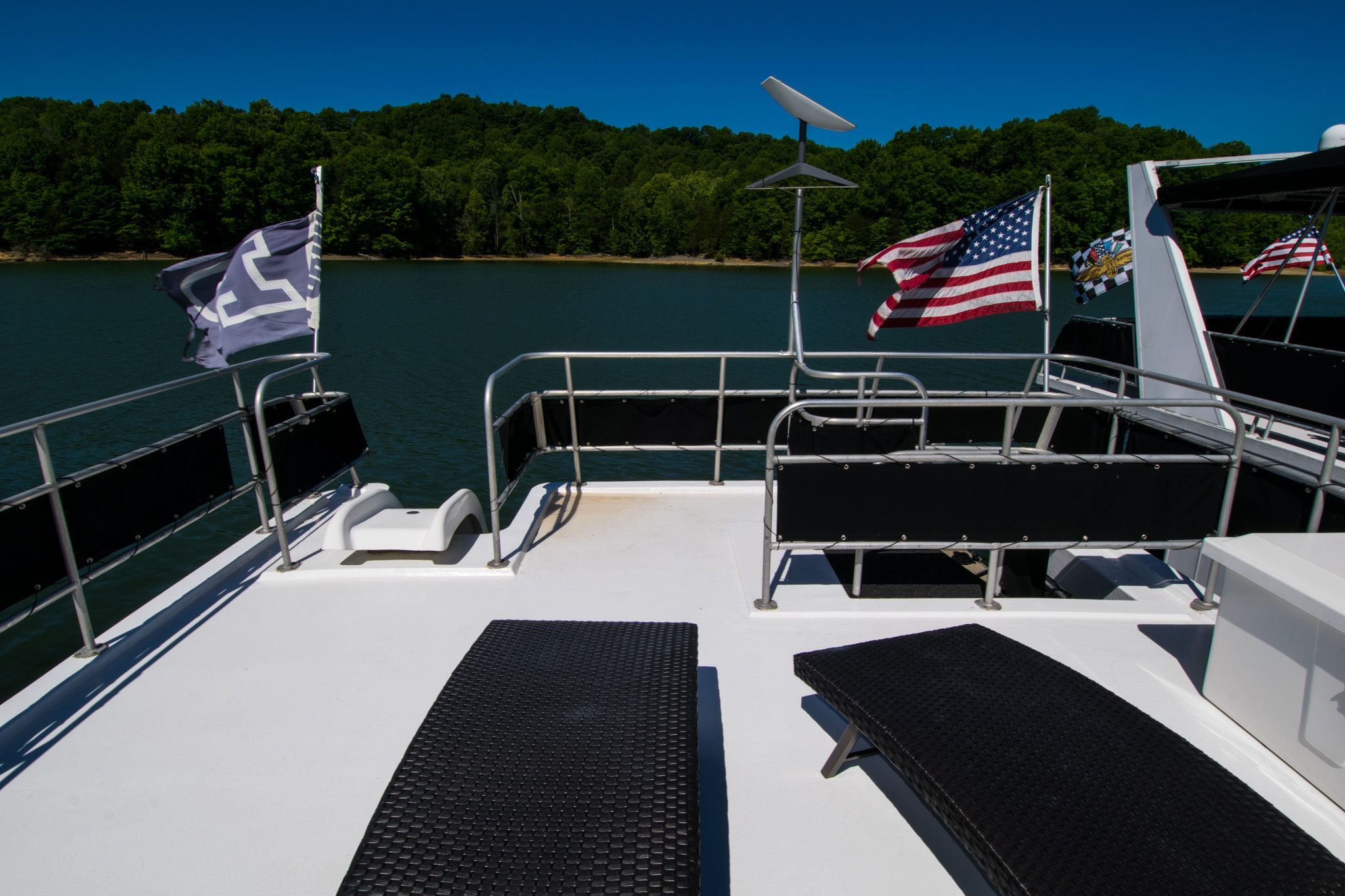 Lakeview 16x70 houseboat, 2003, on a serene lake with flags.