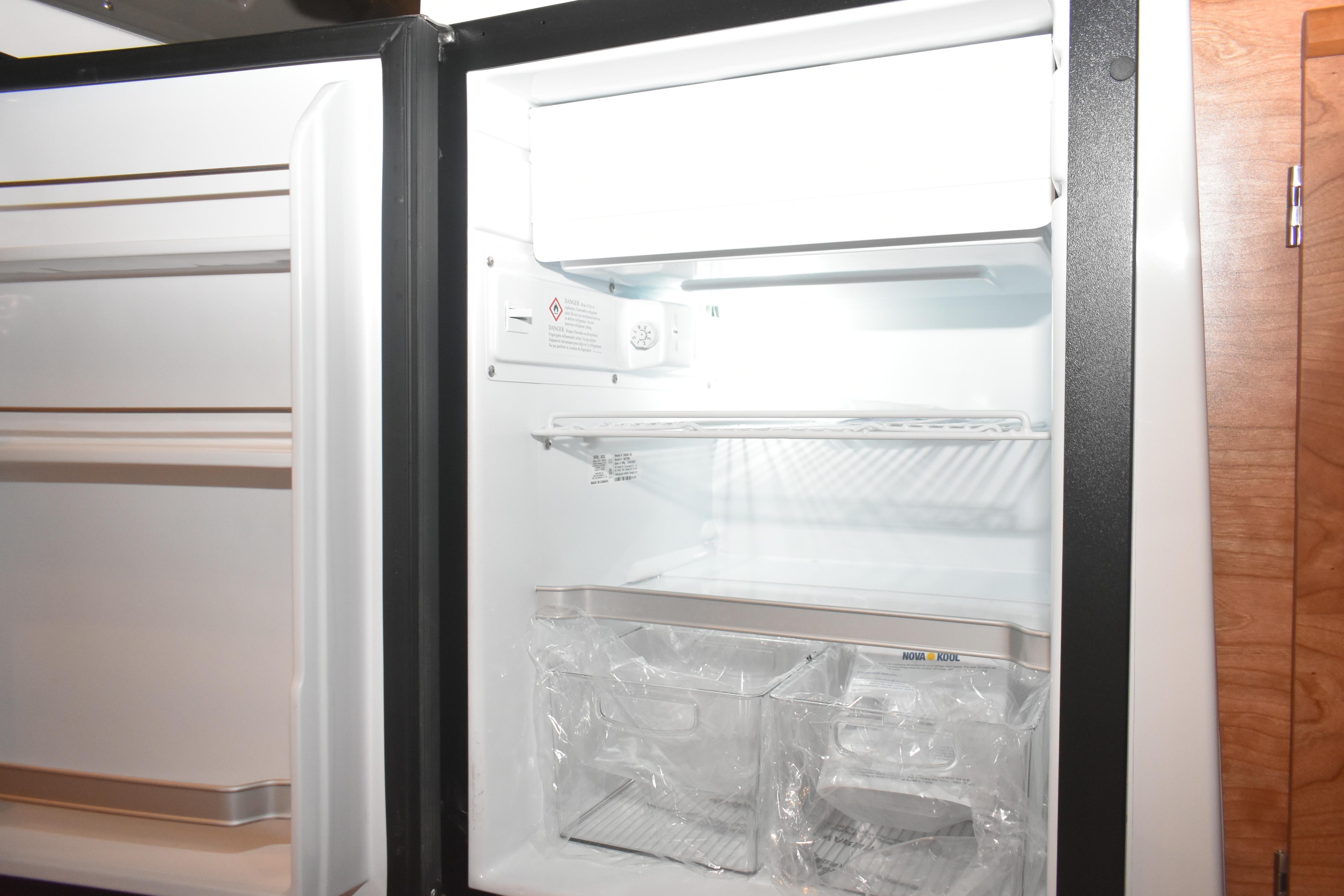 Open refrigerator inside 2026 Cutwater C-248 Coupe boat, showcasing shelves and storage compartments.